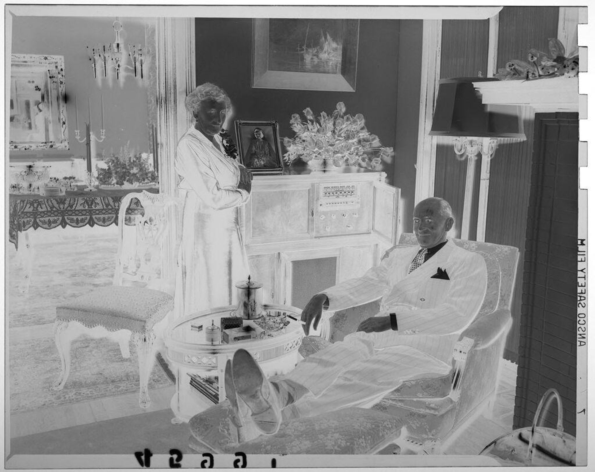 Untitled (middle-aged couple posed in living room with man in chair and woman standing) by Martin Schweig
