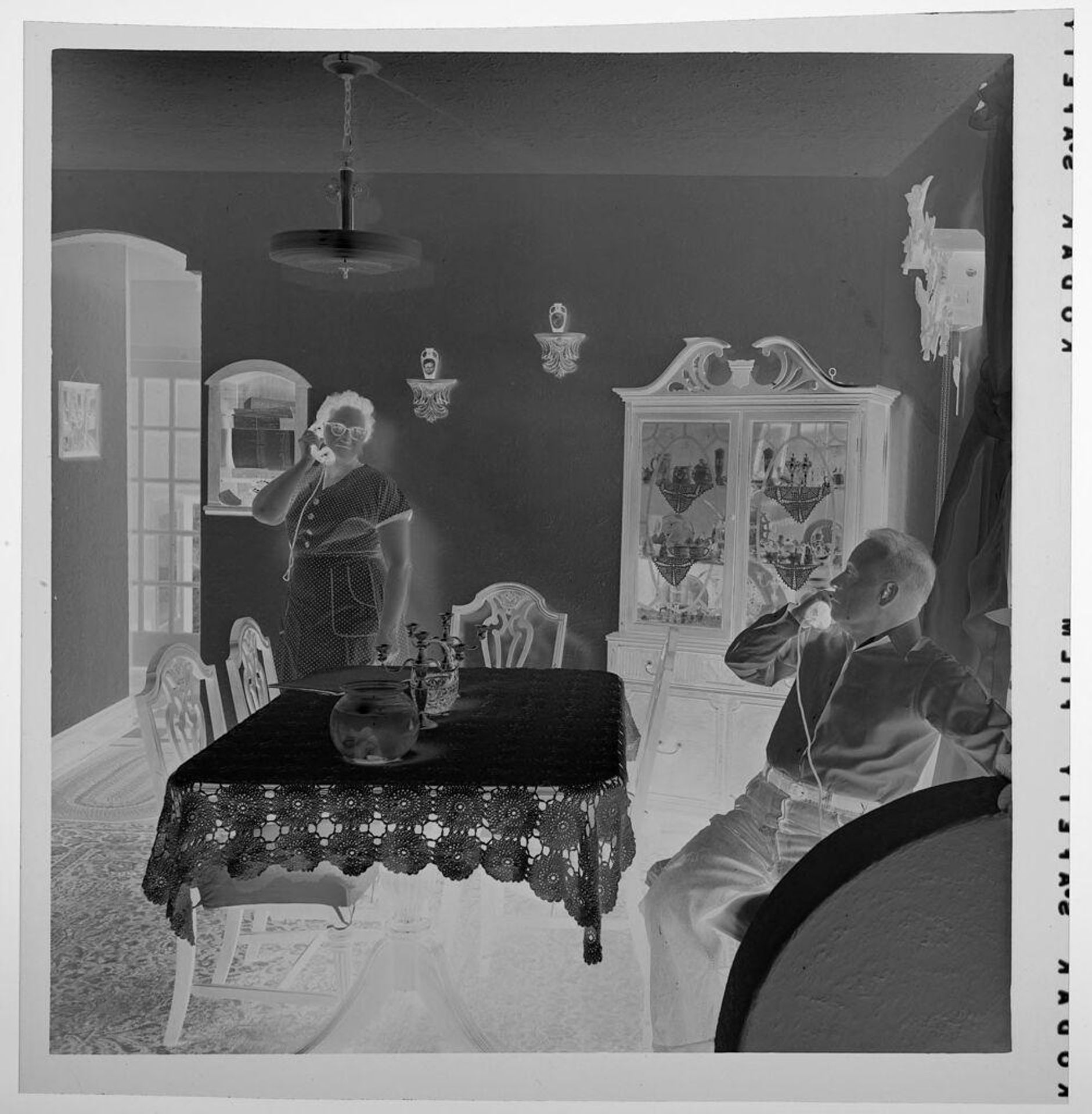 Untitled (man and woman in dining room, both on telephone) by Jack Gould
