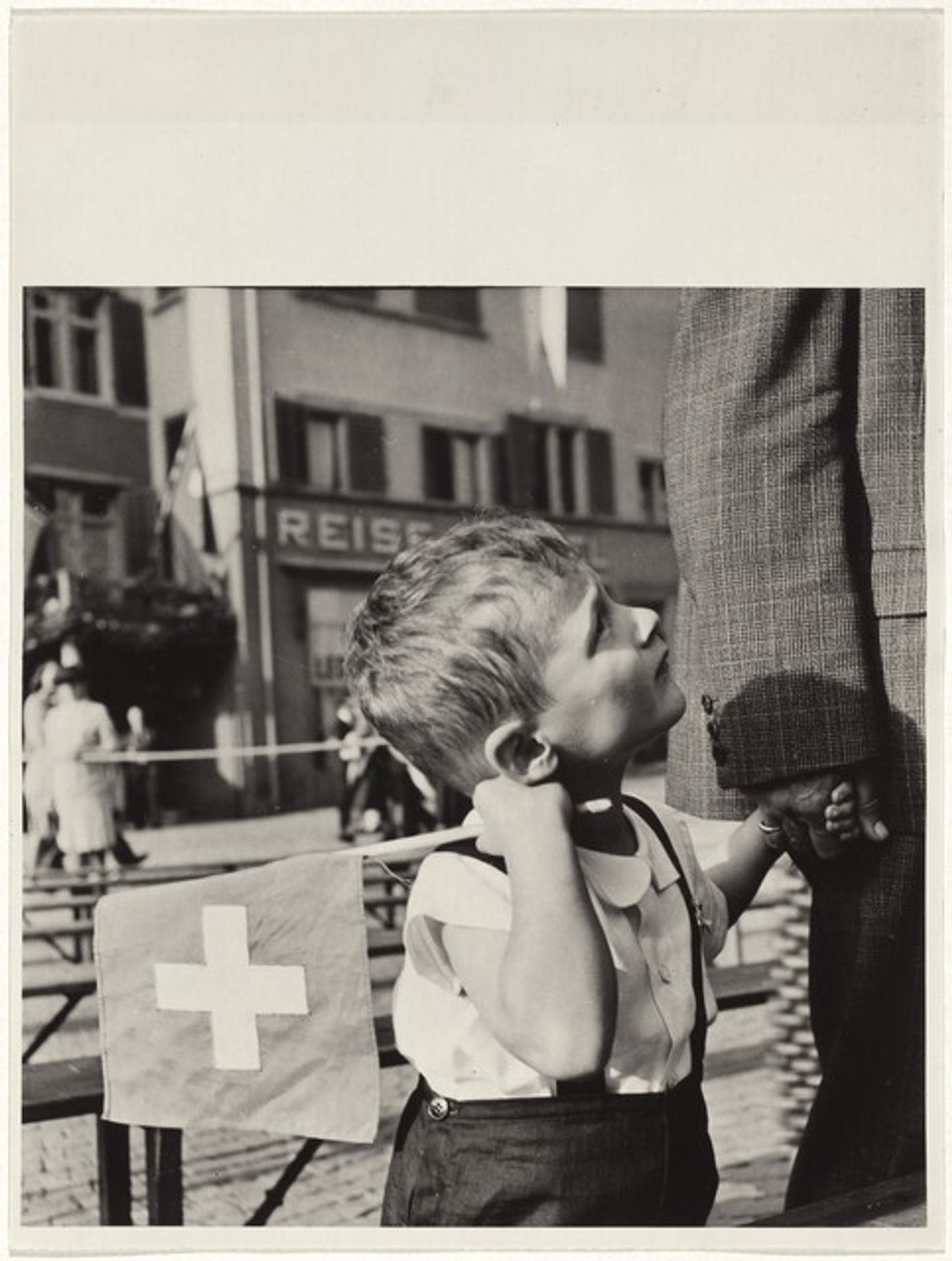 Boy holding flag on national holiday by Robert Frank