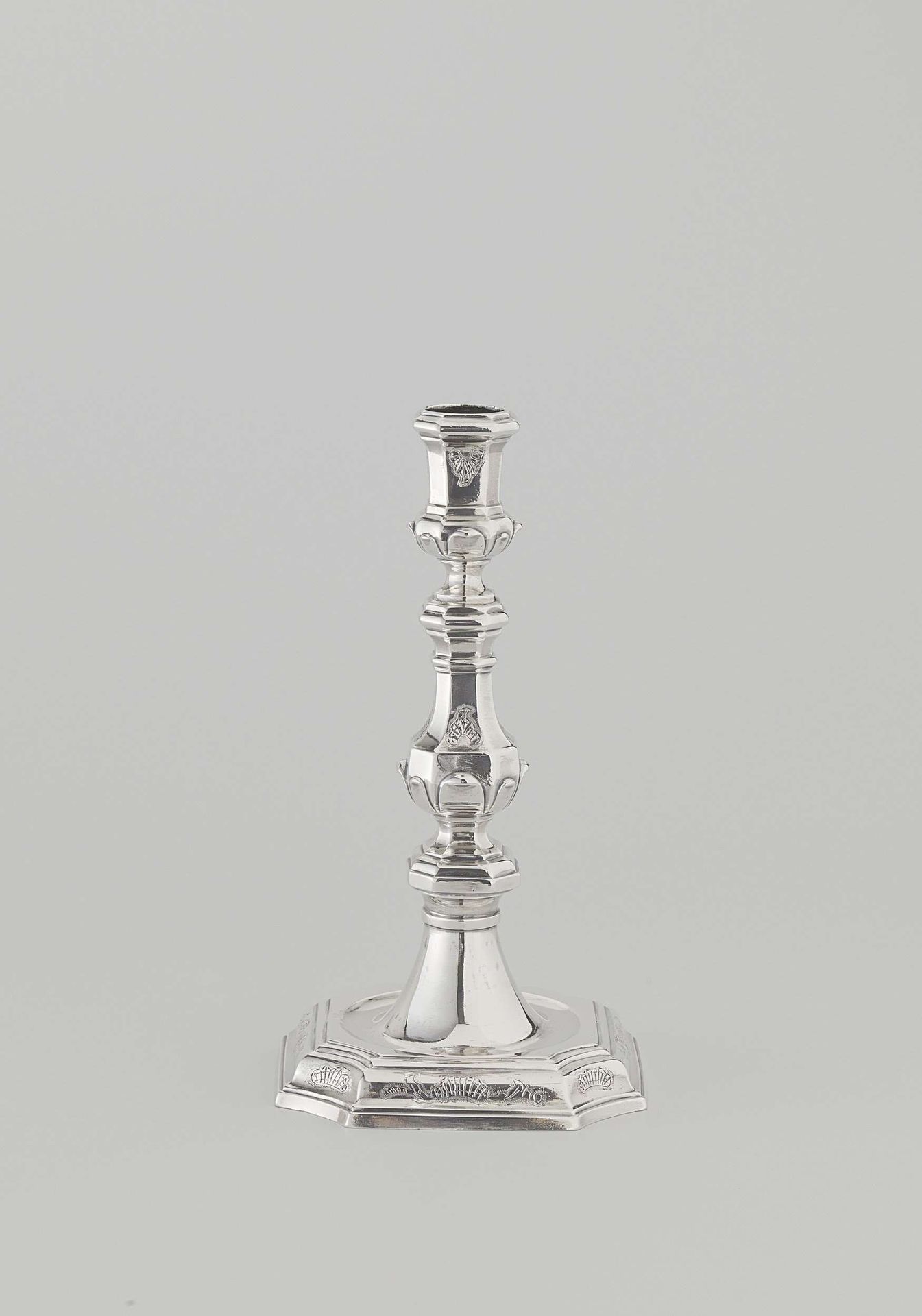 Kandelaar van zilver met achthoekige voet en achthoekige balustervormige stam met kaarsenhouder. Gegraveerd met rocaillemotieven. by Louis de Haan