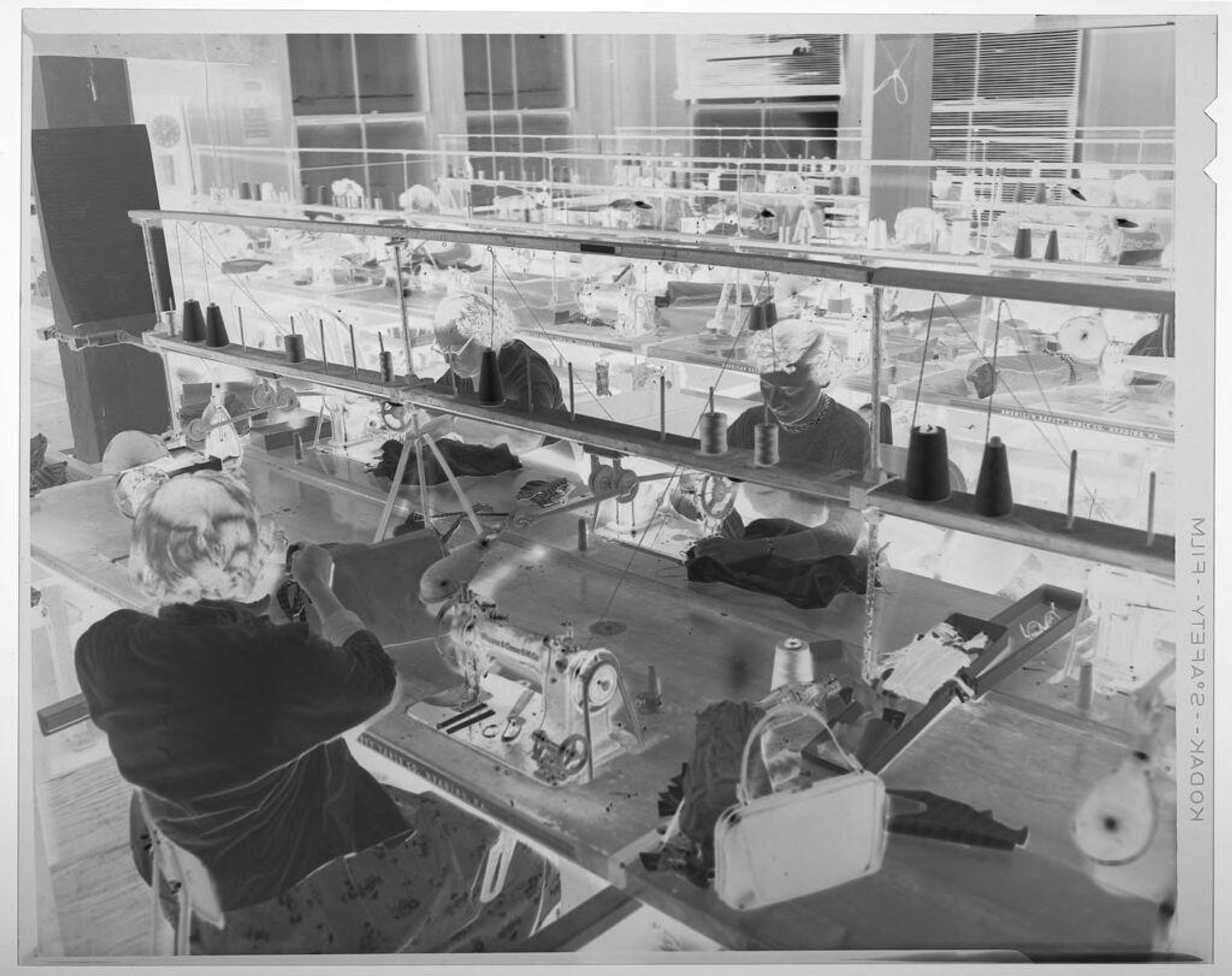 Untitled (three women working on sewing machines in warehouse room) by Martin Schweig