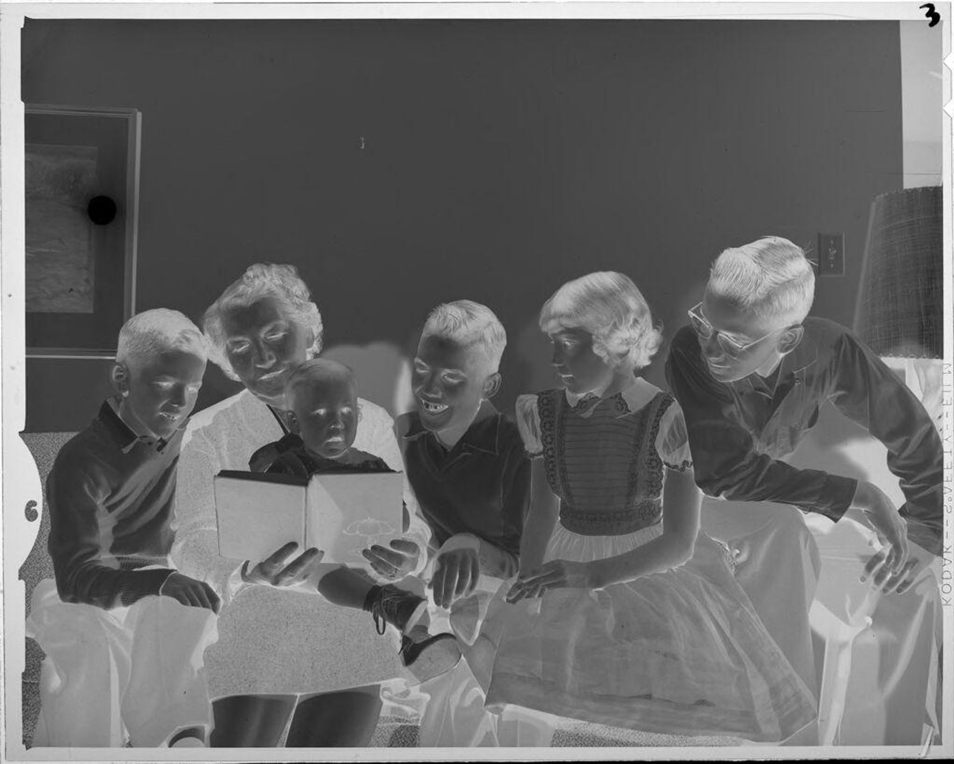 Untitled (woman reading book to children on couch) by Lucian and Mary Brown