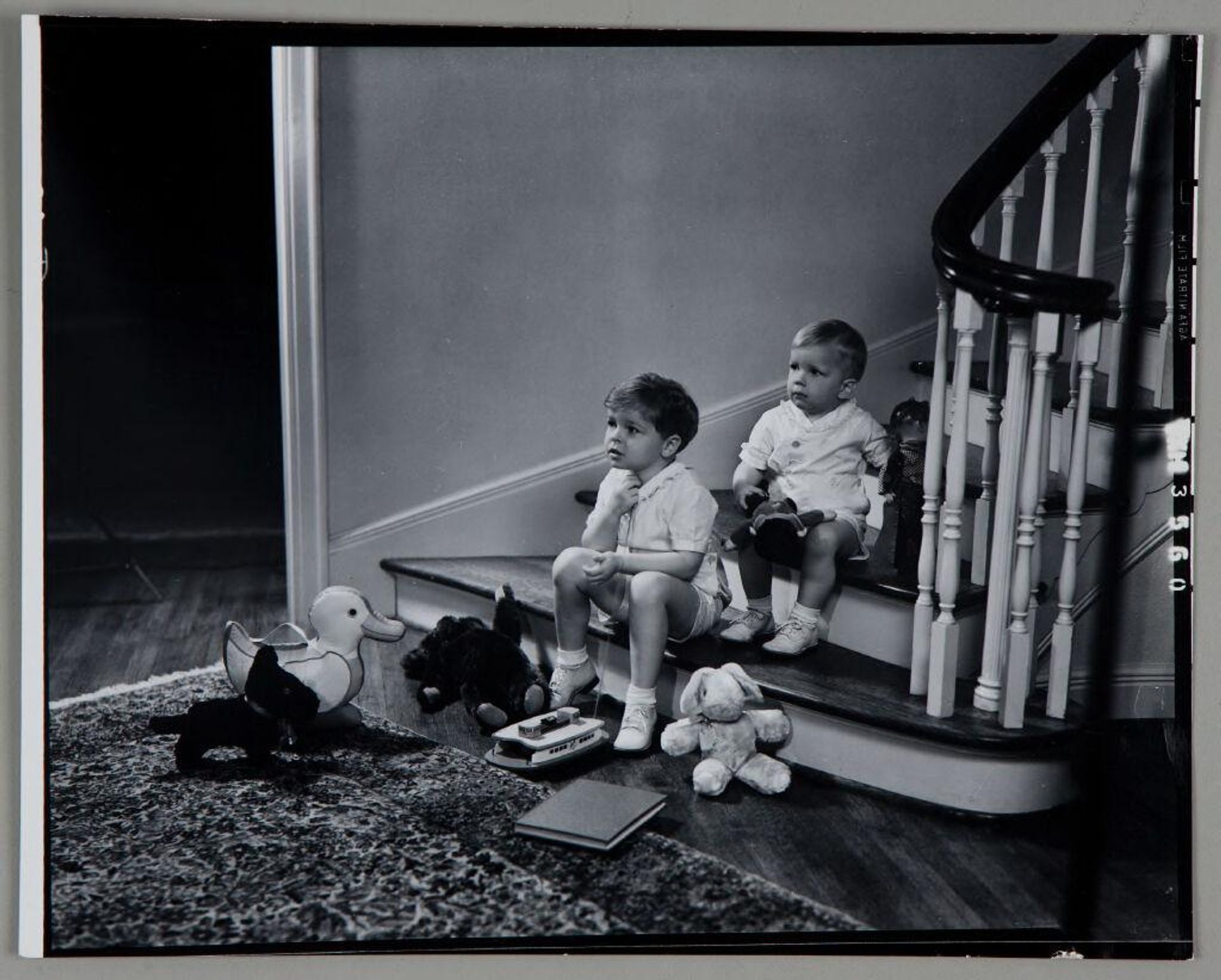 Untitled (two children sitting on bottom of staircase with toys strewn around them) by Paul Gittings