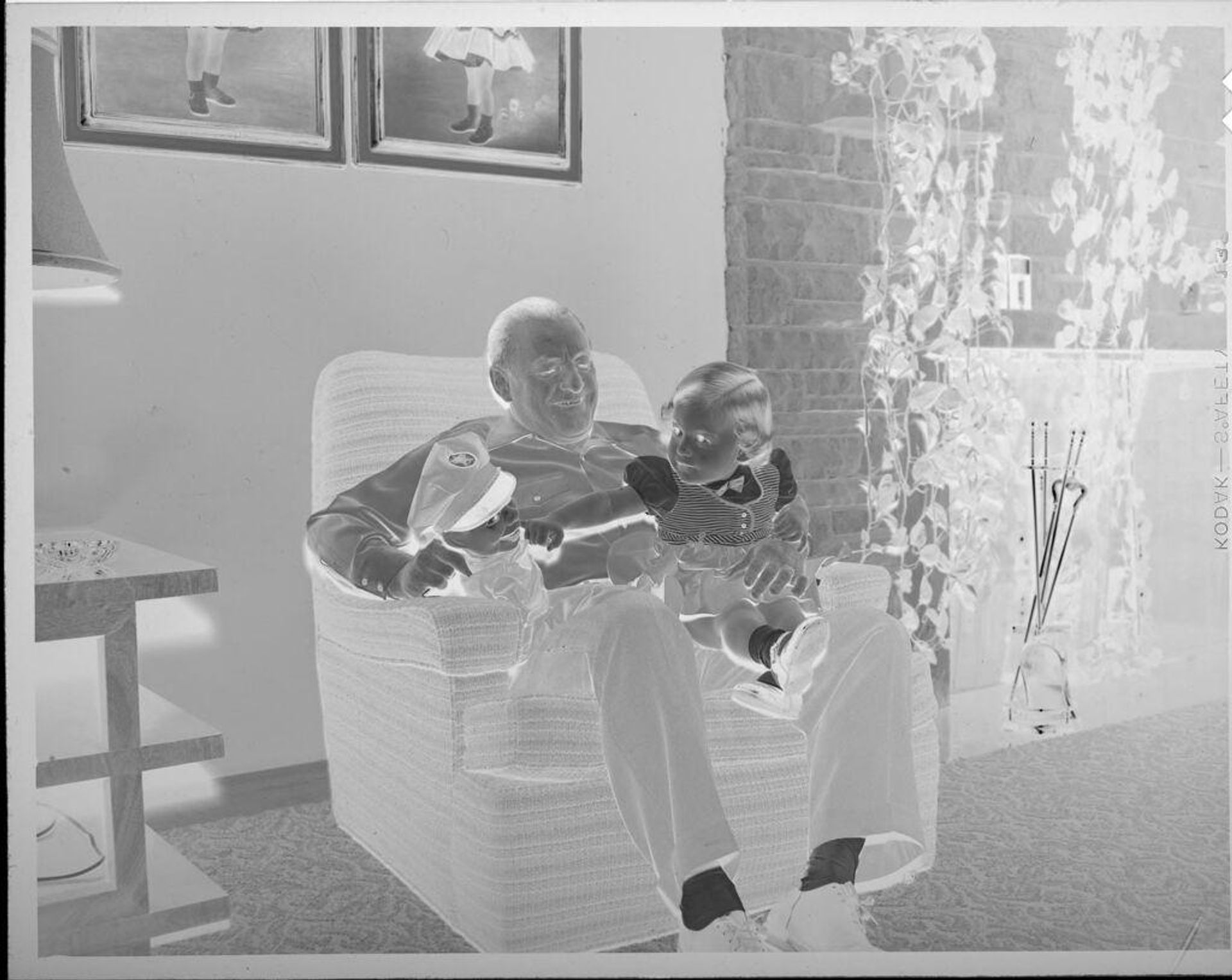 Untitled (man in chair holding puppet and baby) by Lucian and Mary Brown