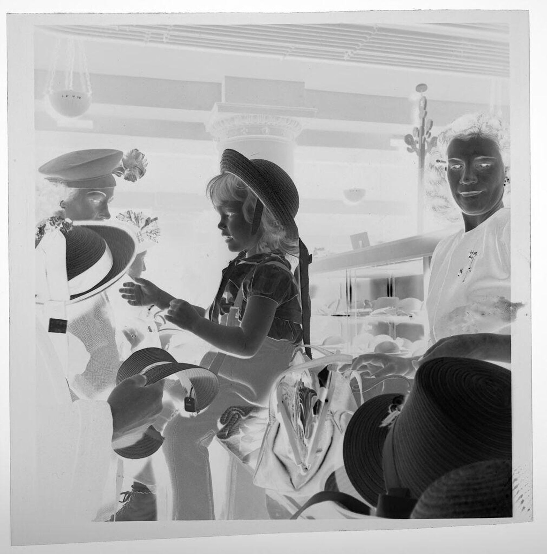 Untitled (seated child trying on hats in store) by Jack Gould