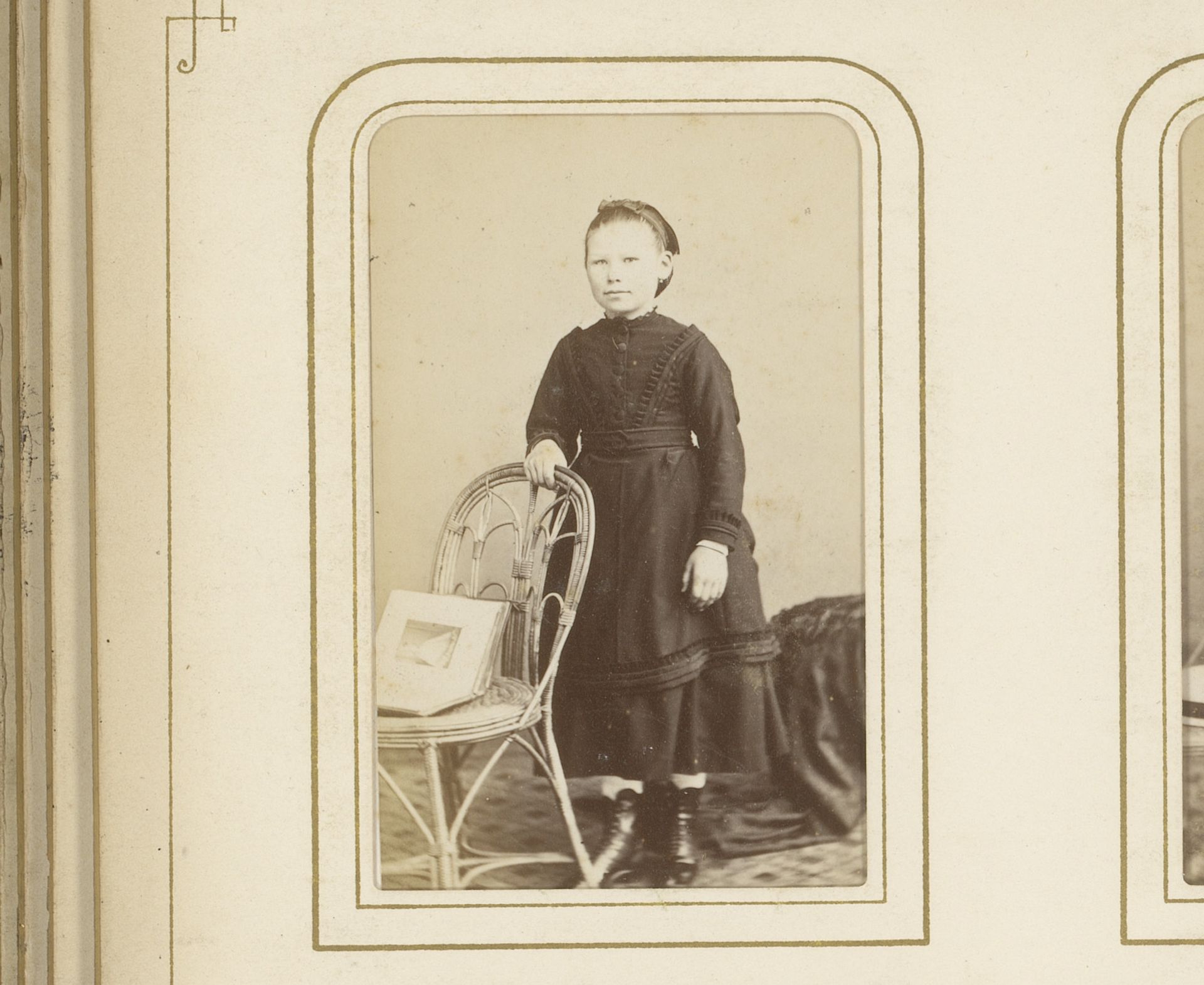 Portret van een meisje, staand bij een stoel met een opengeslagen album by Prosper Bevierre