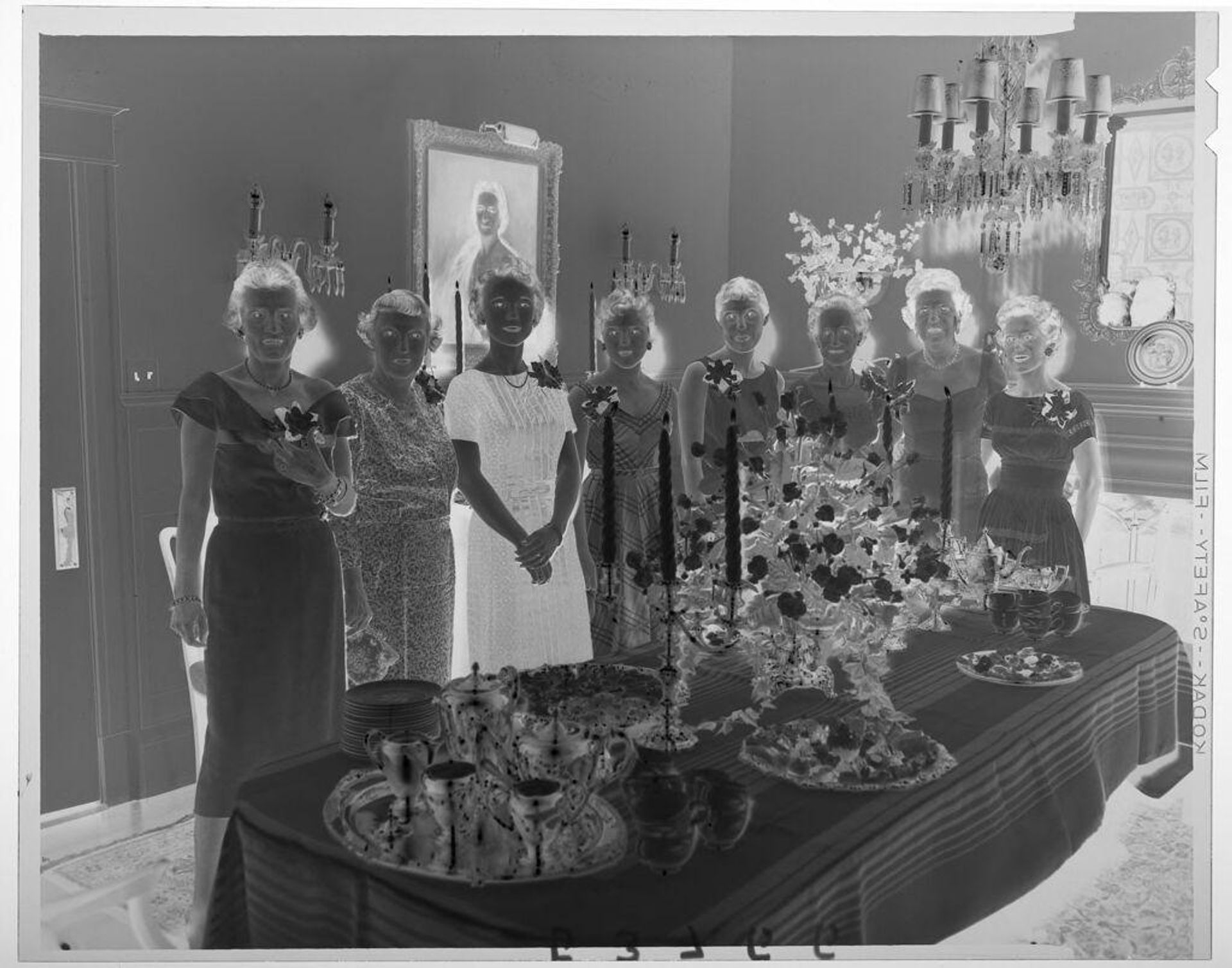 Untitled (eight women in dresses posing behind serving table in fancy dining room) by Martin Schweig