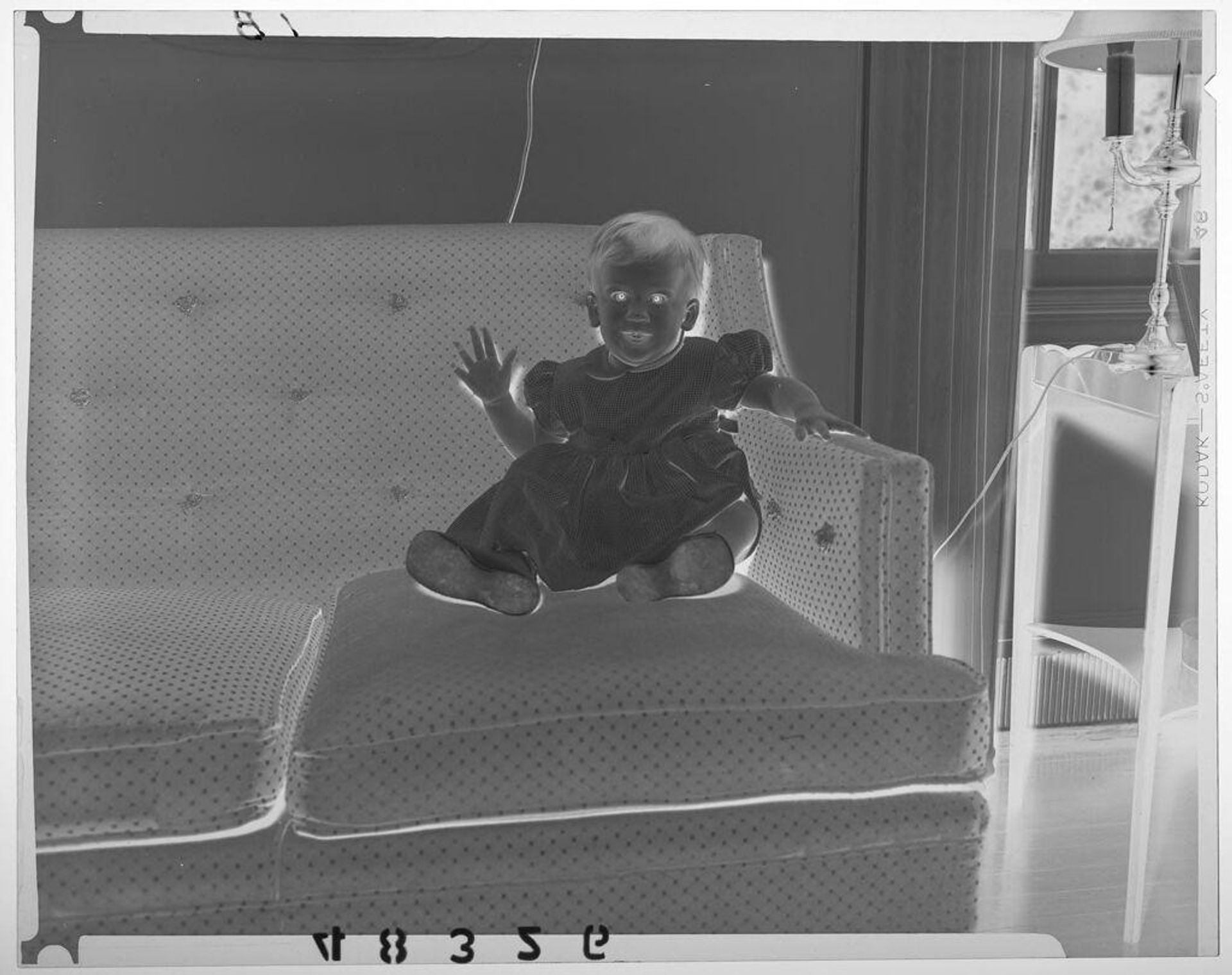 Untitled (baby girl in dress posed sitting on couch) by Martin Schweig