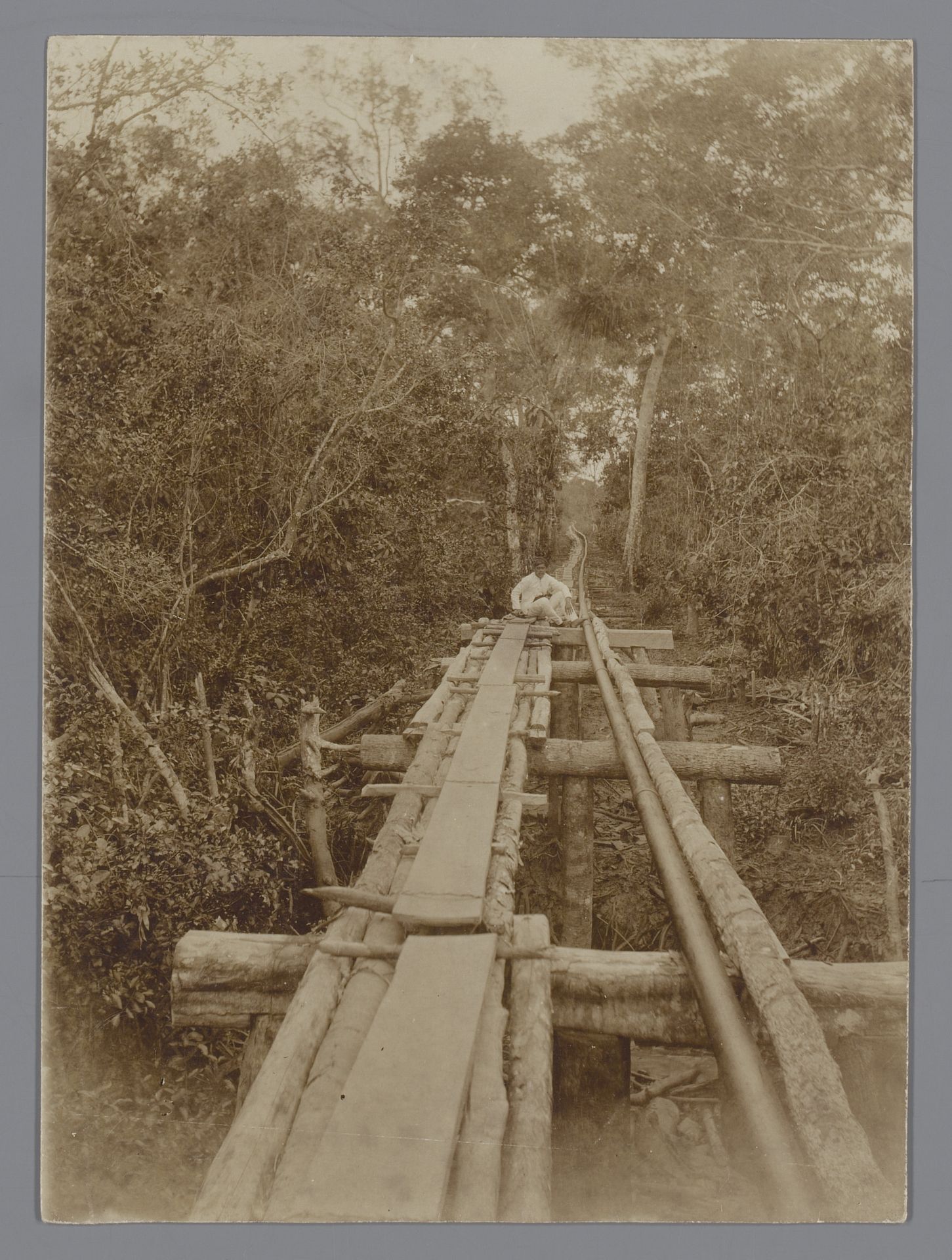 Houten brug van lange planken en boomstammen over een rivier of afgrond, Nederlands-Indië by M. Graadt van Roggen