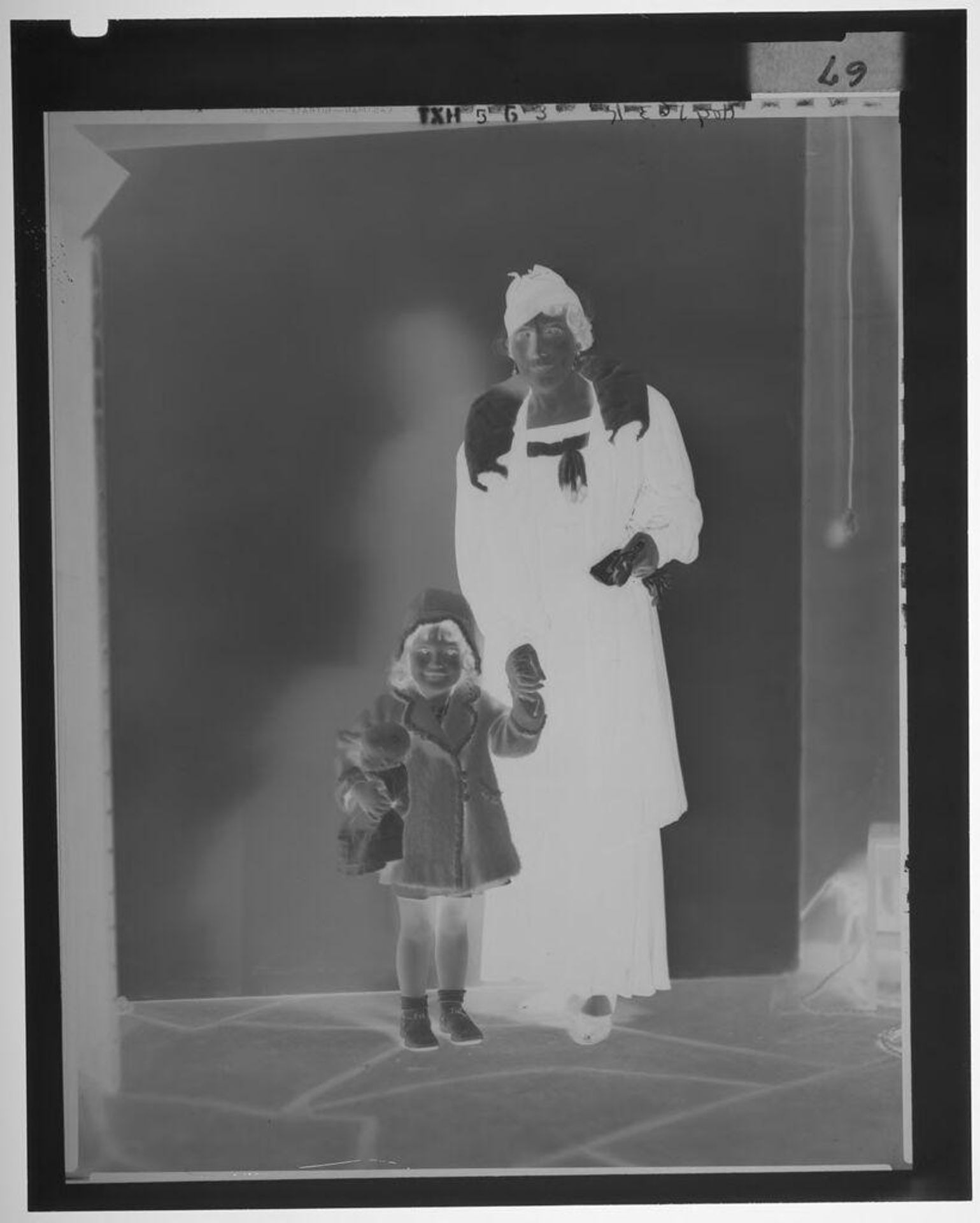 Untitled (woman in hat and stole standing and holding hands with little girl holding doll) by Paul Gittings