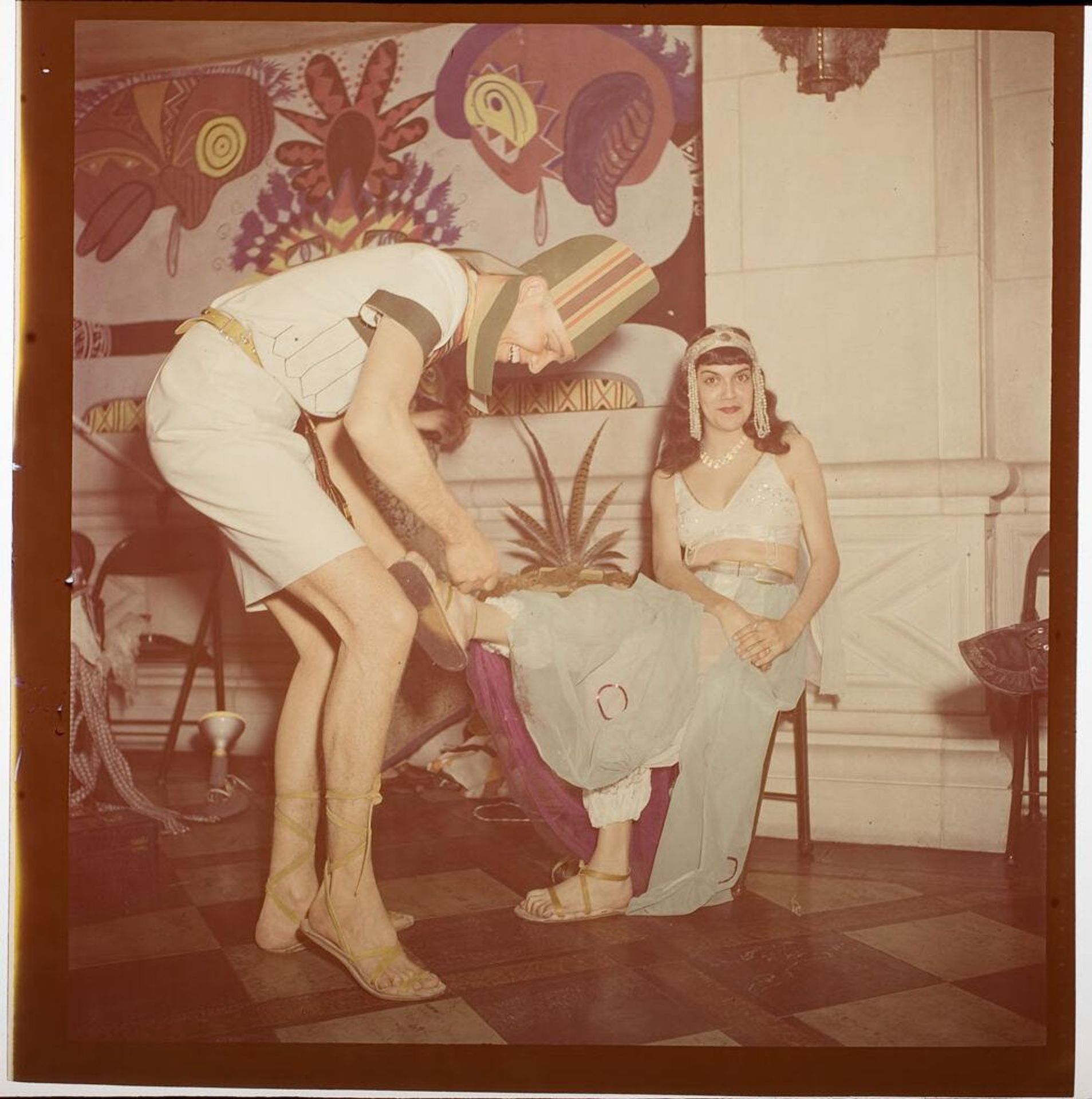 Untitled (couple in costume at Beaux Arts Ball, man fixing woman's shoe) by Jack Gould