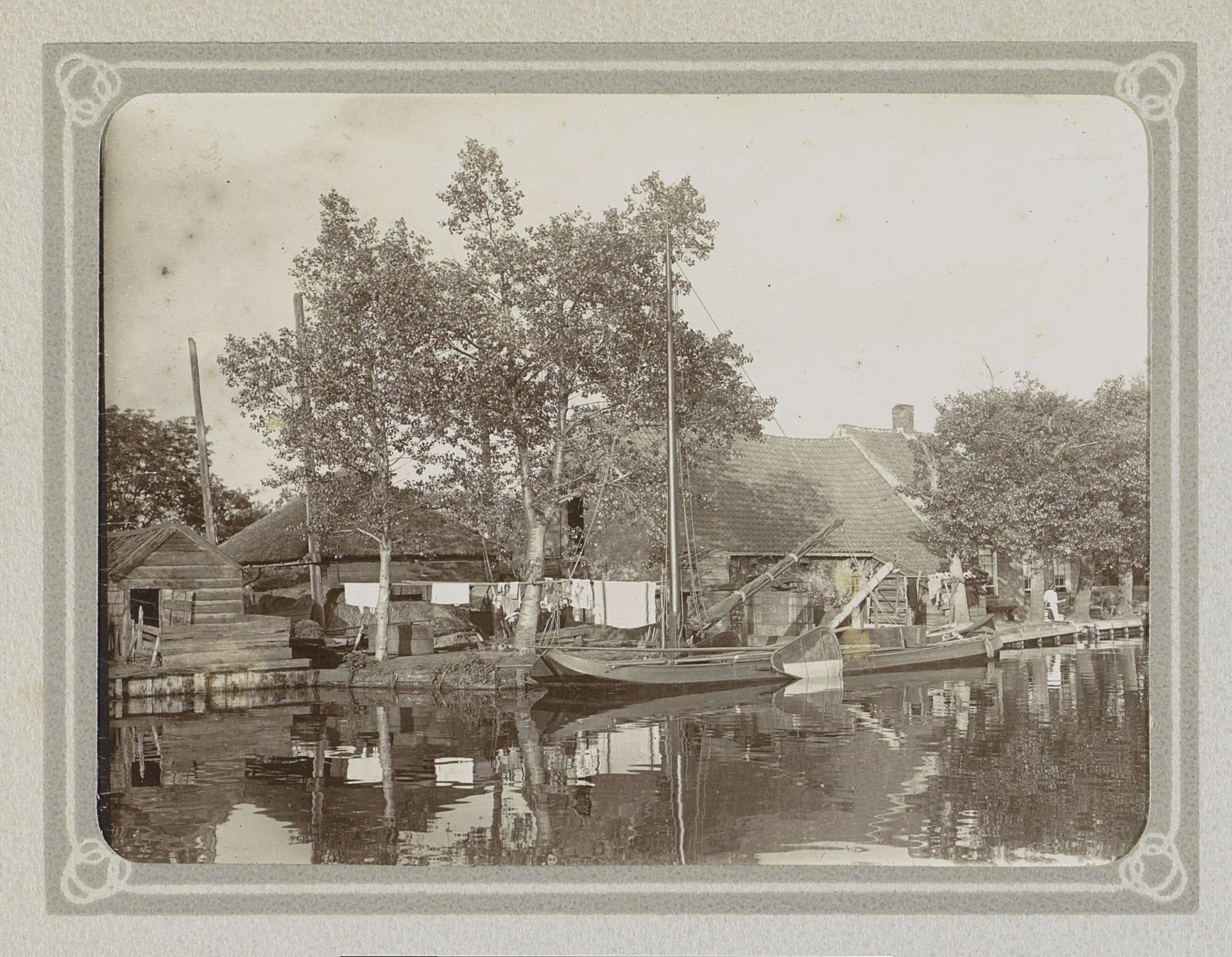 Boerderij met een schuur en een hooiberg aan een water, op de voorgrond een platbodem by Folkert Idzes de Jong