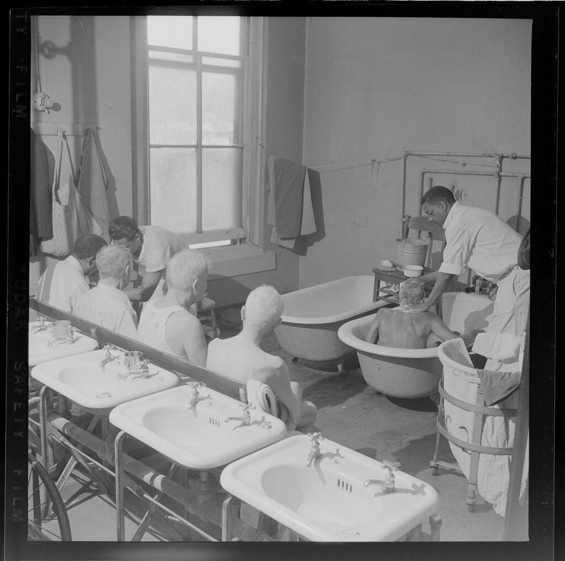 Untitled (boys next to bathtubs and sinks) by Jack Gould