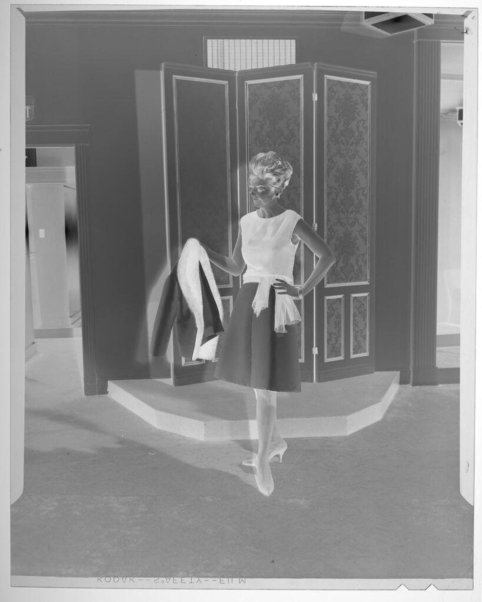 Untitled (fashion portrait of woman wearing sleevless shirt and skirt holding fur lined coat) by Martin Schweig