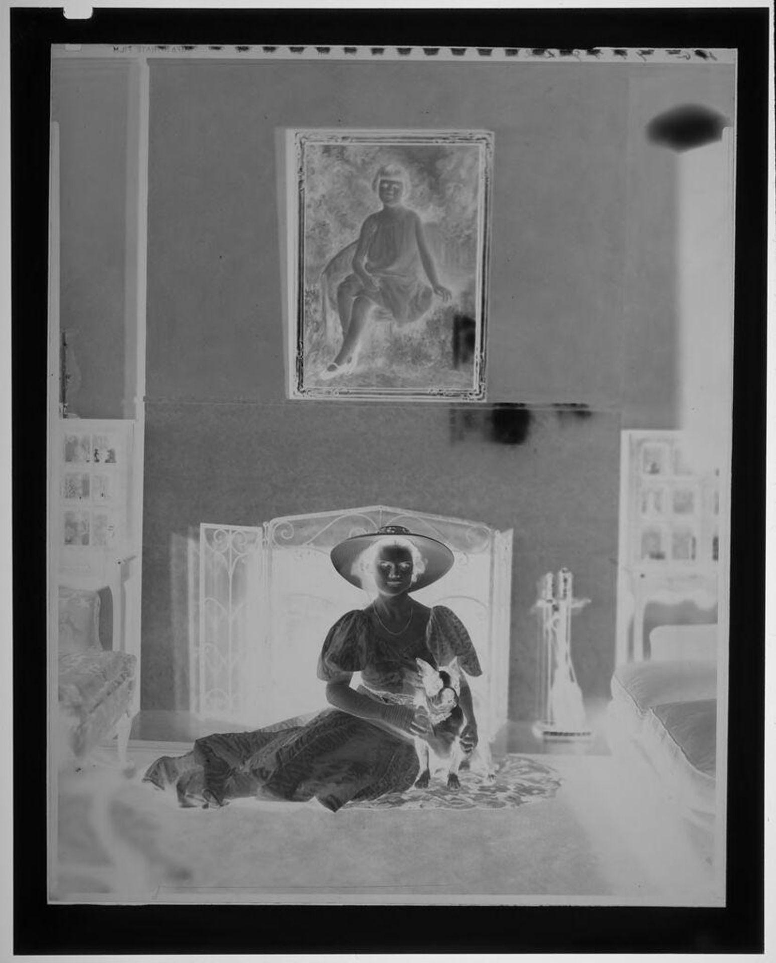 Untitled (woman in hat and long dress seated on floor by fireplace under large portrait of girl) by Paul Gittings