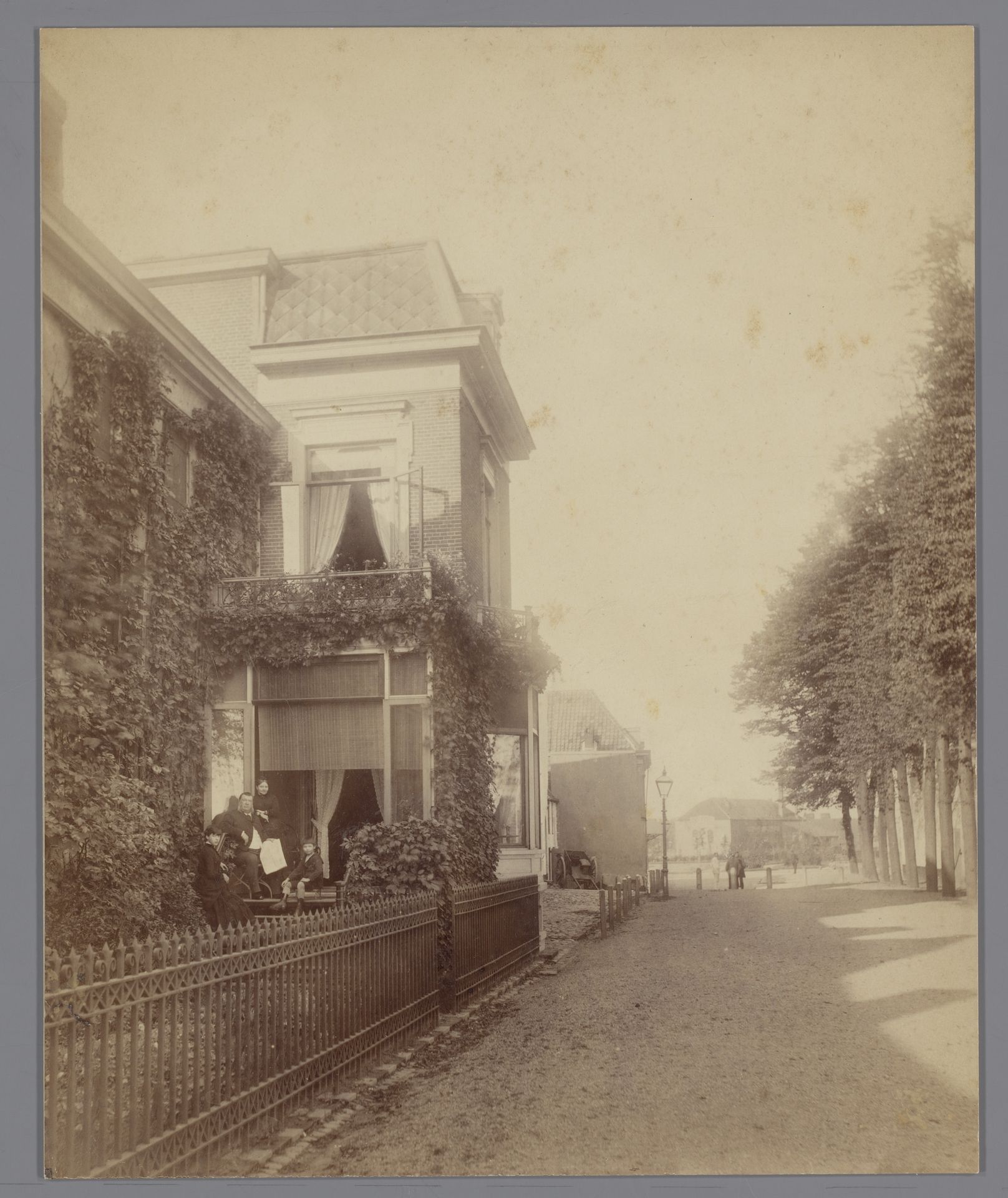 Straatgezicht, met man en vrouw en twee kinderen voor een huis by Wilhelm Ivens