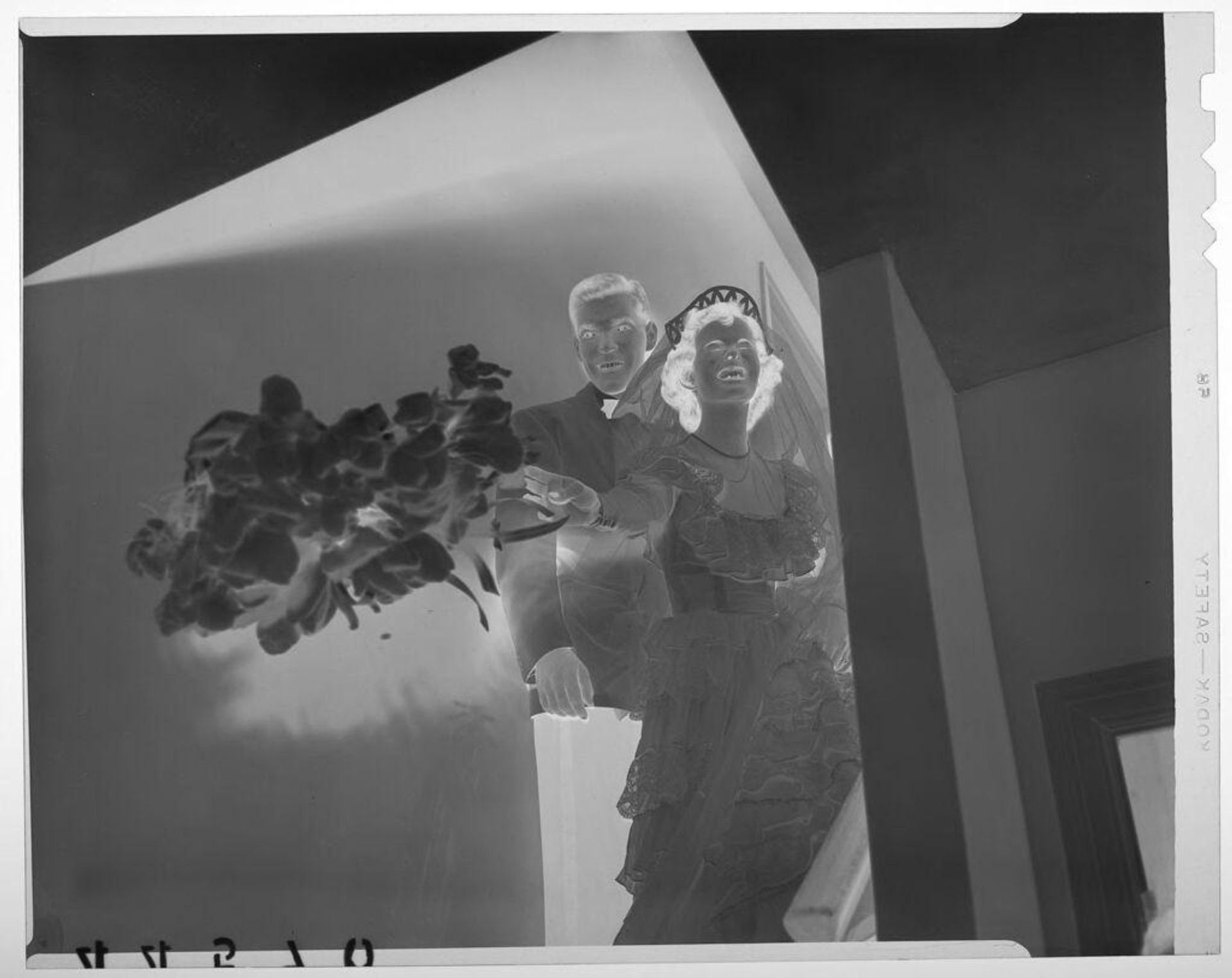 Untitled (bride posed next to groom throwing bouquet down from staircase) by Martin Schweig