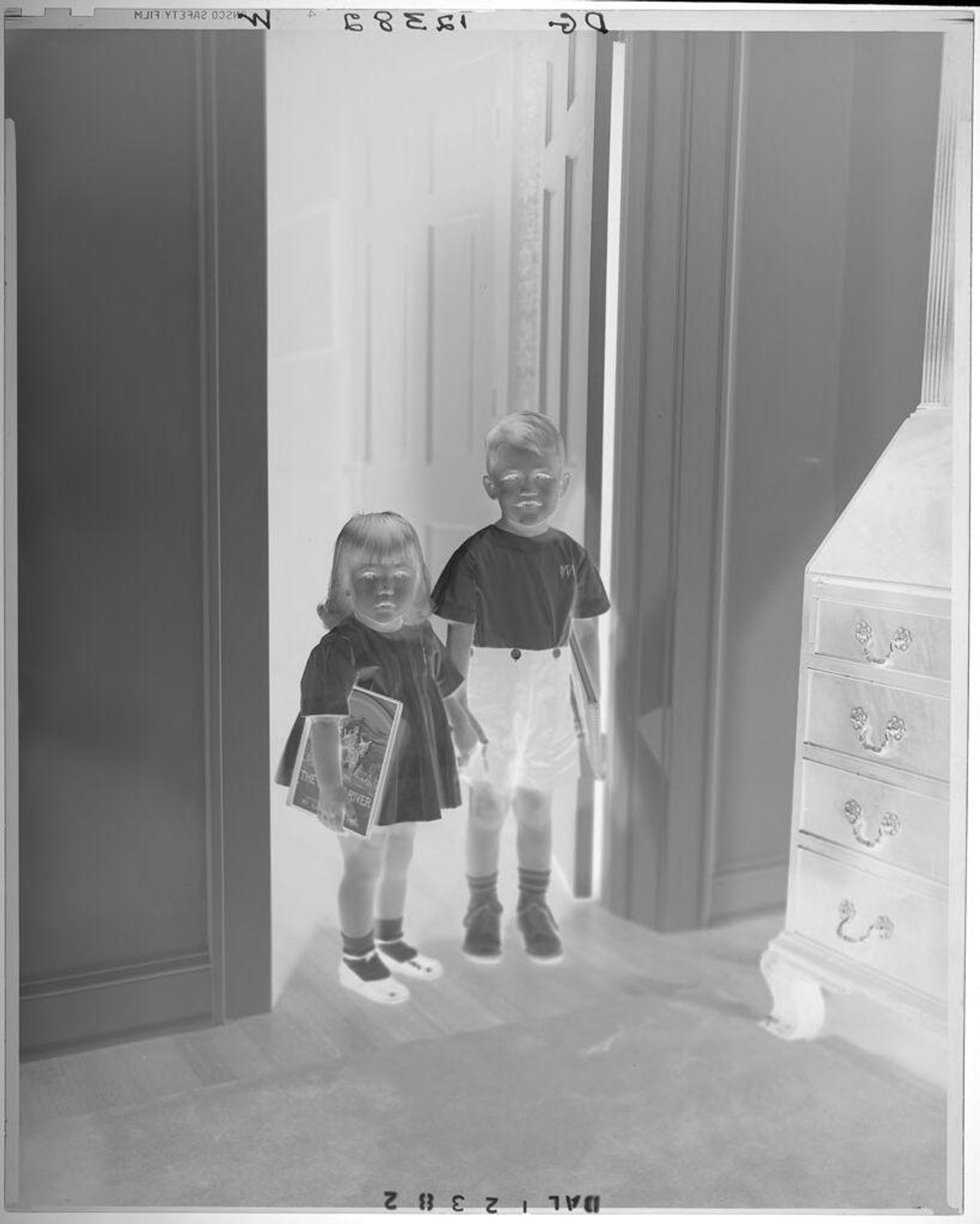 Untitled (young brother and sister in doorway holding hands and holding books) by Paul Gittings