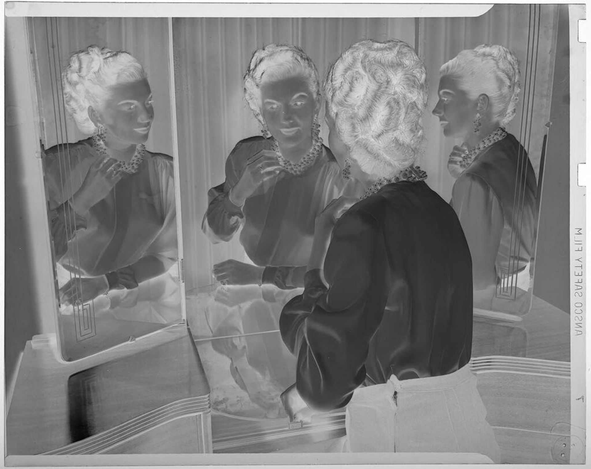 Untitled (woman looking in three-way mirror, fixing necklace) by Jack Gould