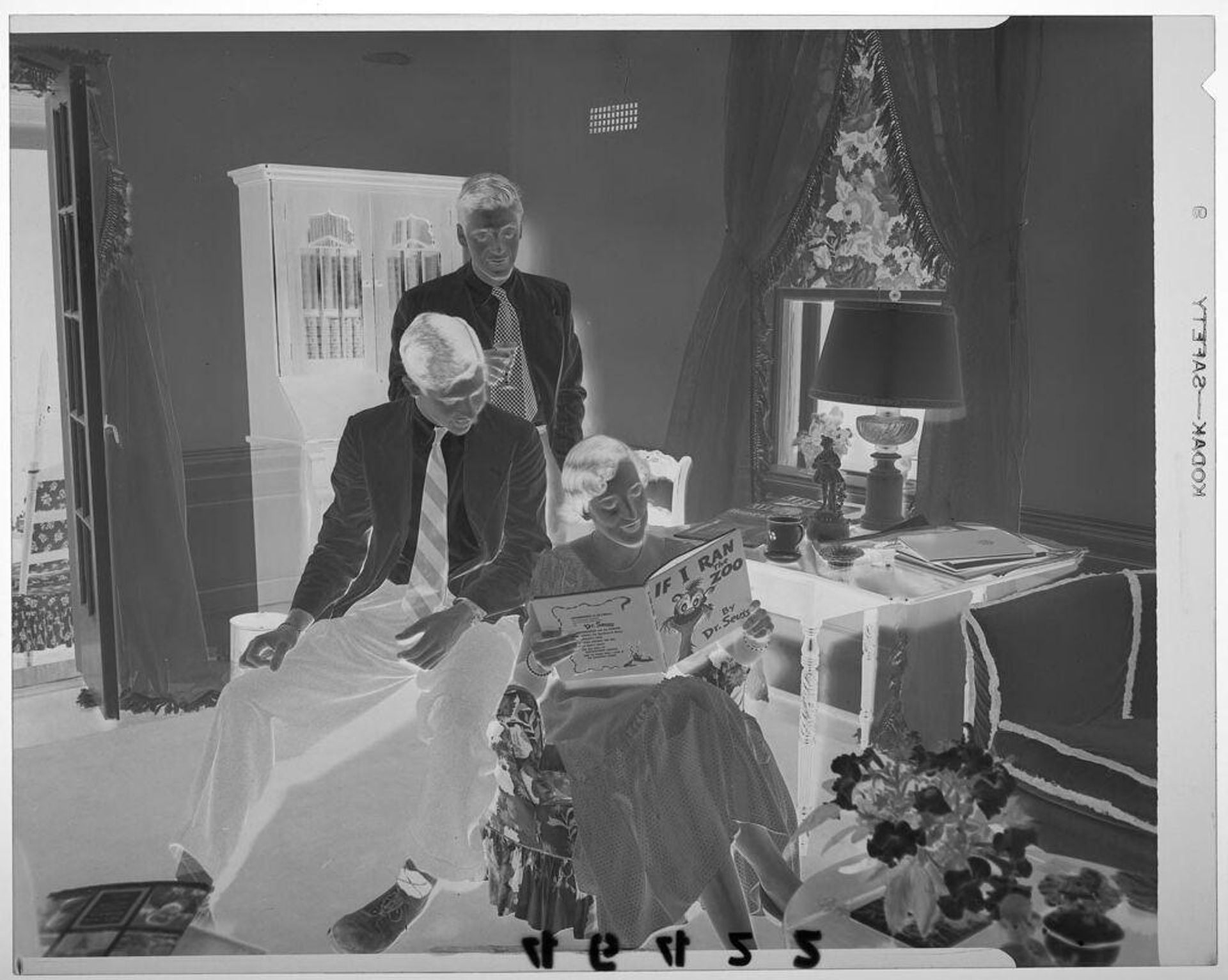 Untitled (two young men posed with young woman reading Dr. Seuss book in living room) by Martin Schweig