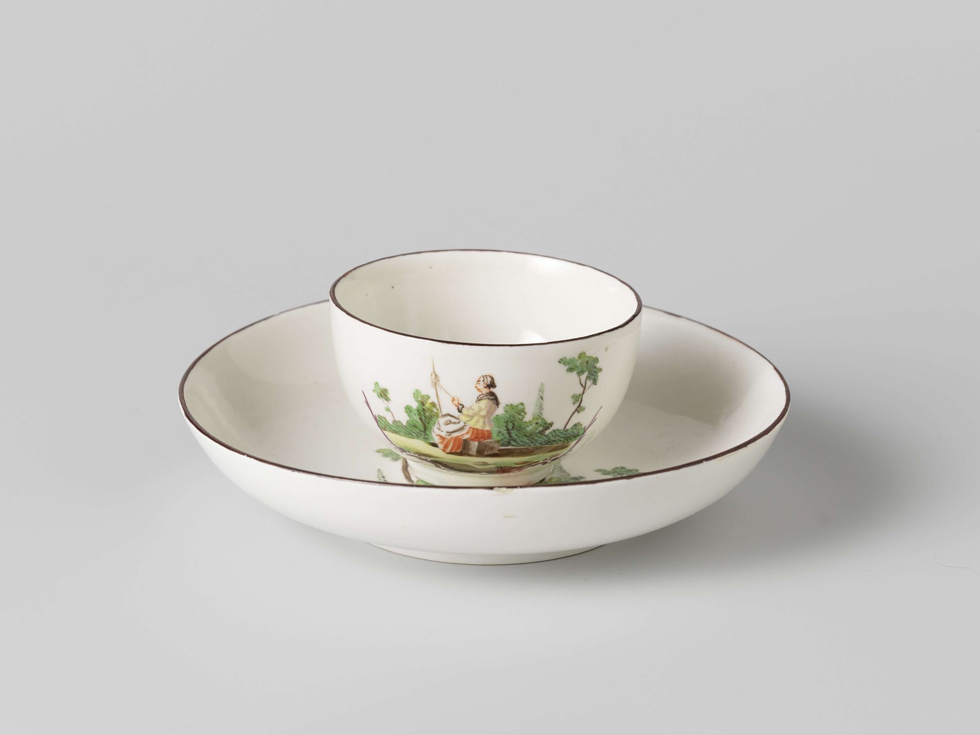 Kop zonder oor en schotel, veelkleurig beschilderd met een vrouw in landschap waaronder rocailleornament by Weesper porseleinfabriek