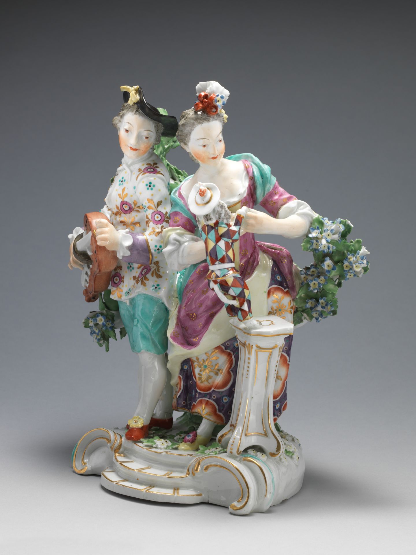 Youth playing hurdy-gurdy, girl teaching dog dressed as harlequin to dance by Derby Porcelain Manufactory