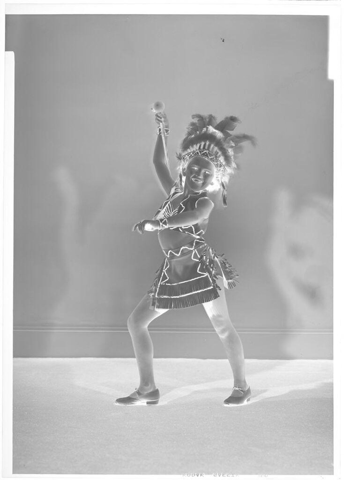 Untitled (girl in headdress and uniform with baton, left foot forward) by John Deusing