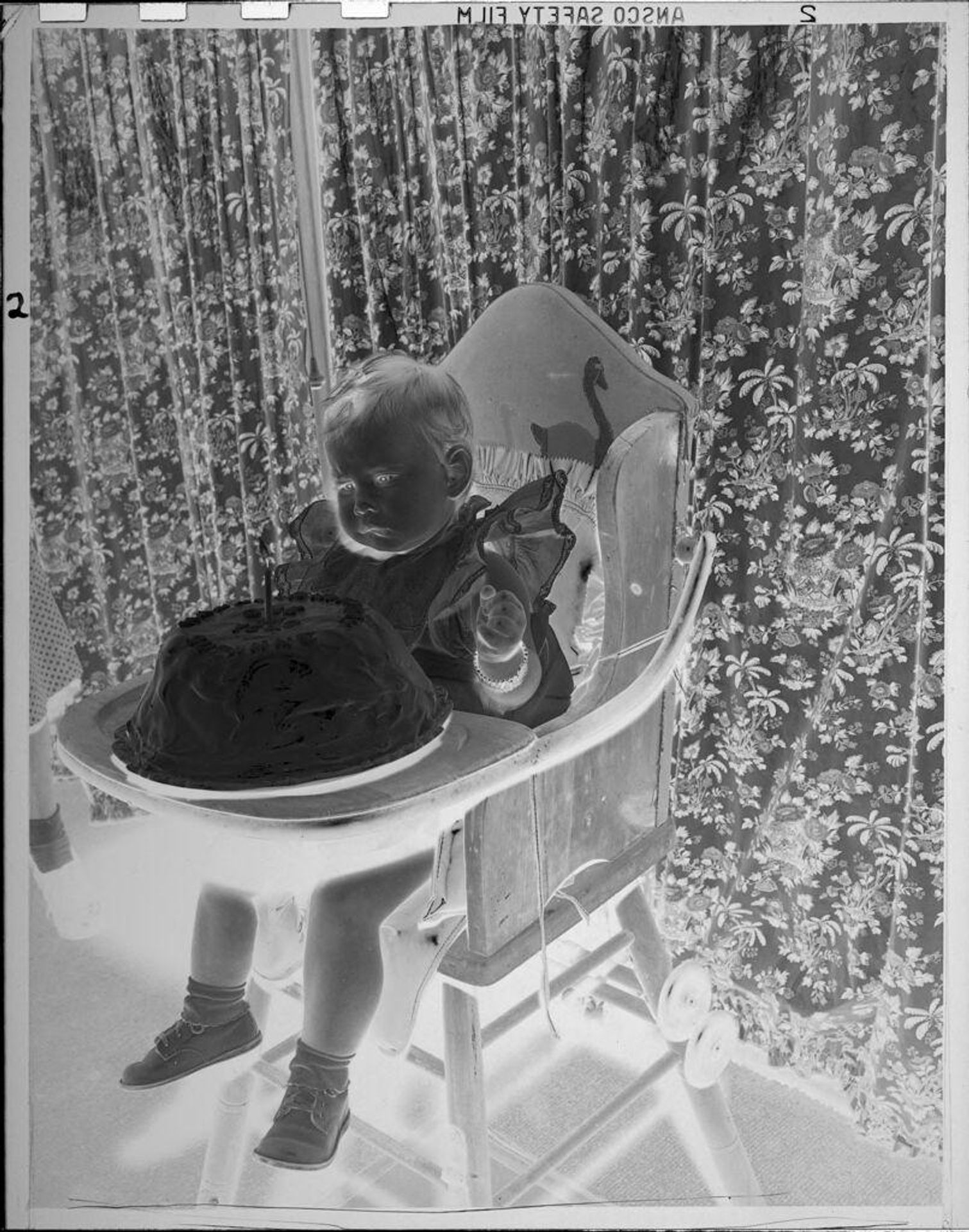 Untitled (baby in high chair with birthday cake) by Lucian and Mary Brown