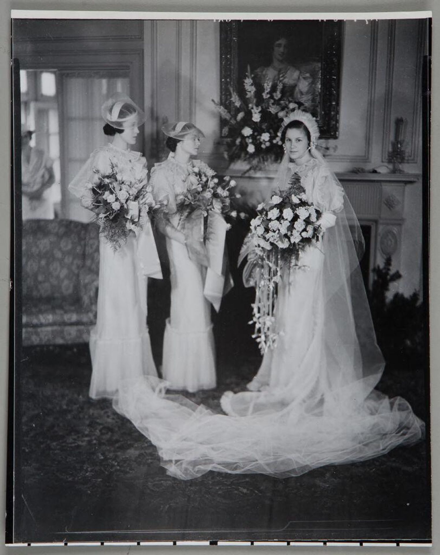 Untitled (full length portrait of two bridesmaids looking at bride, all carry roses) by Paul Gittings