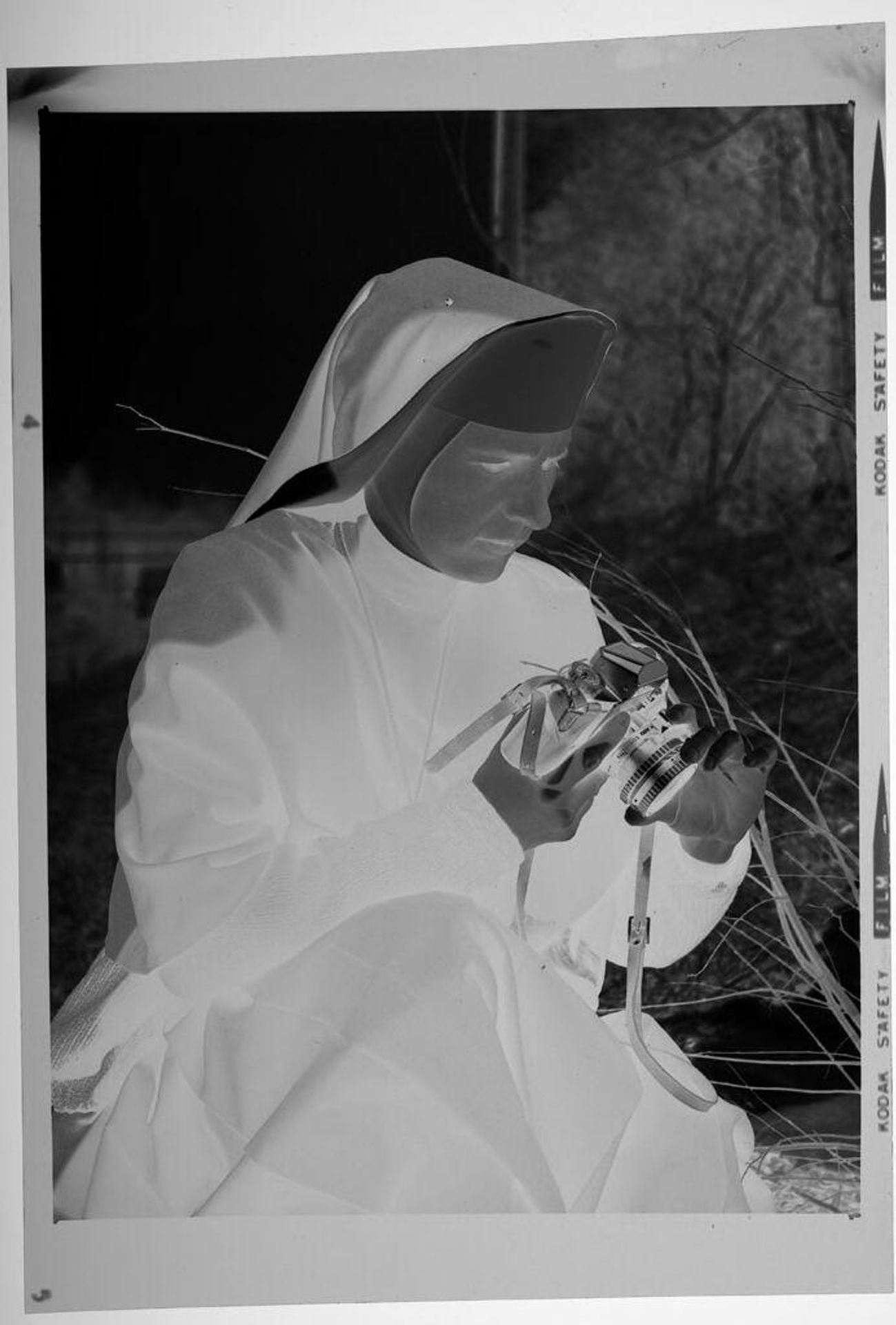 Untitled (nun inspecting 35mm camera outdoors) by Martin Schweig