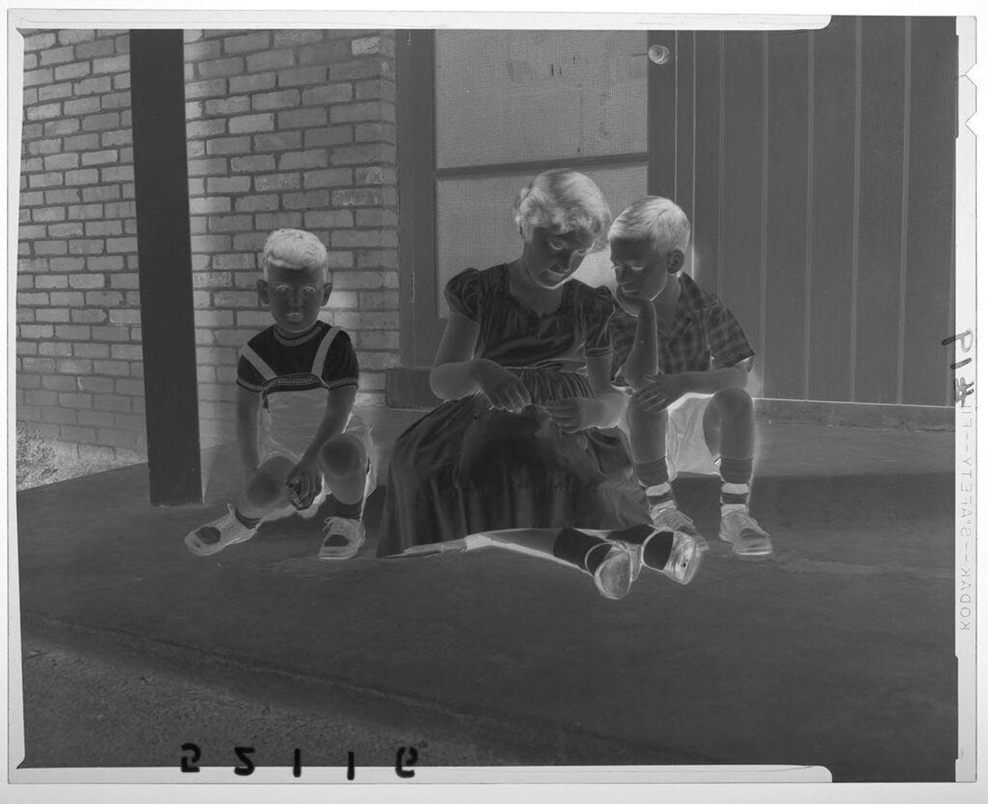 Untitled (girl and two young boys sitting outside of house door with two looking at bracelet) by Martin Schweig