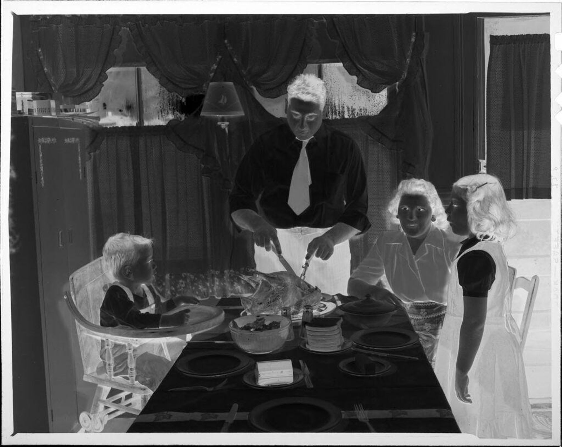 Untitled (man carving turkey for family at table) by Robert Burian
