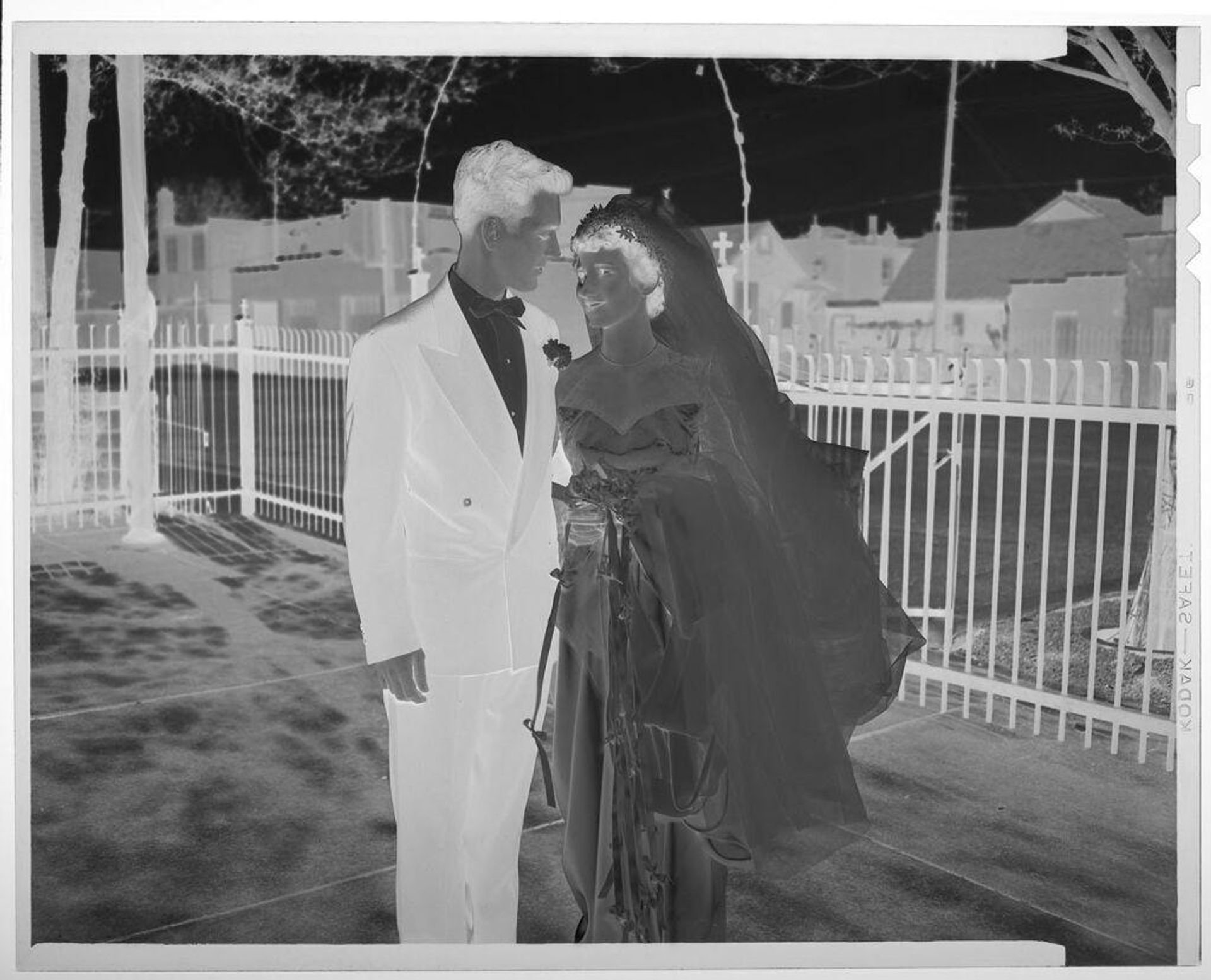 Untitled (bridge and groom posed looking at each other in courtyard with iron fence in background) by Martin Schweig