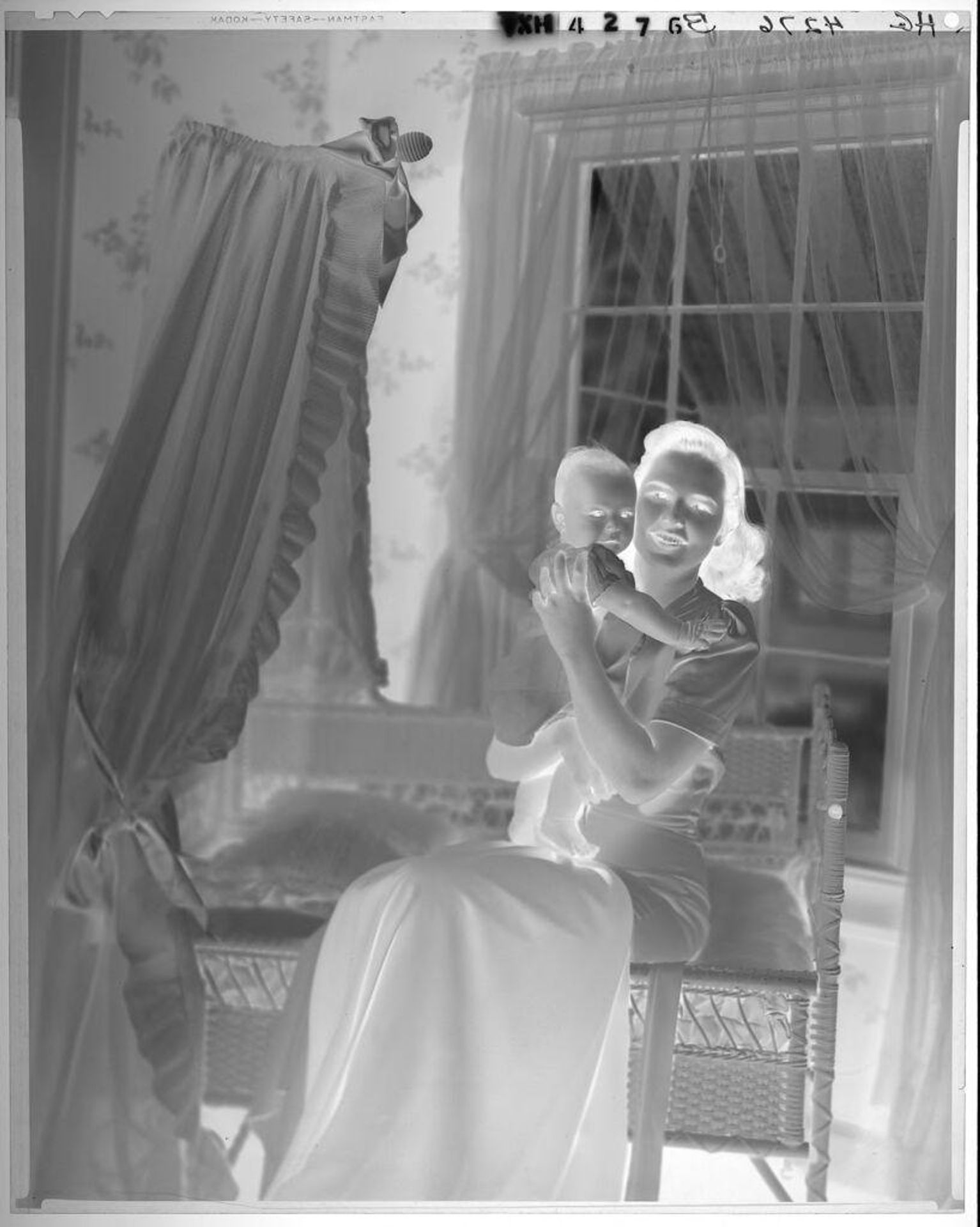 Untitled (woman seated at edge of bassinet, holding baby up) by Paul Gittings
