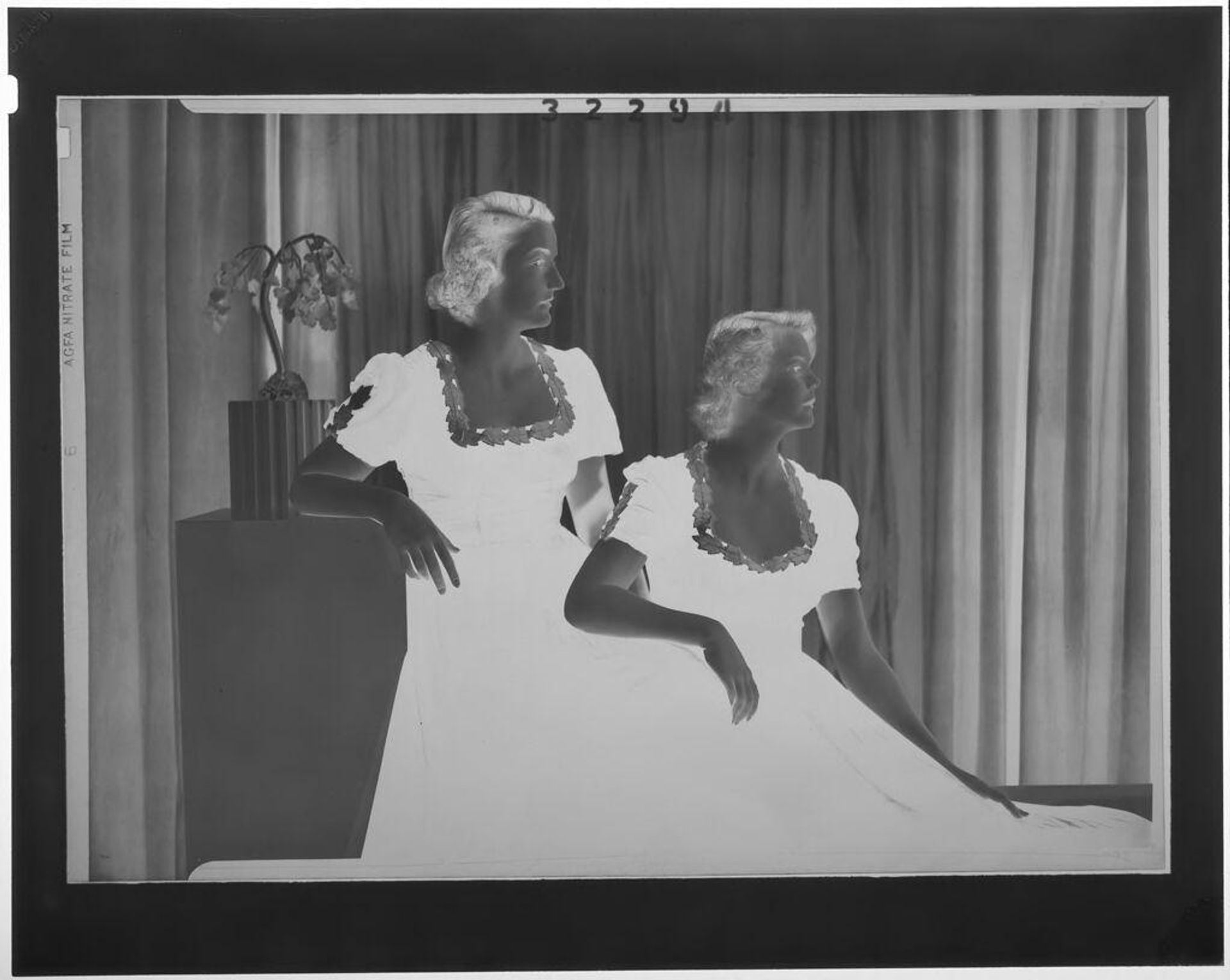 Untitled (studio portrait of two women seated in profile wearing formal dresses with leaf edges) by Martin Schweig