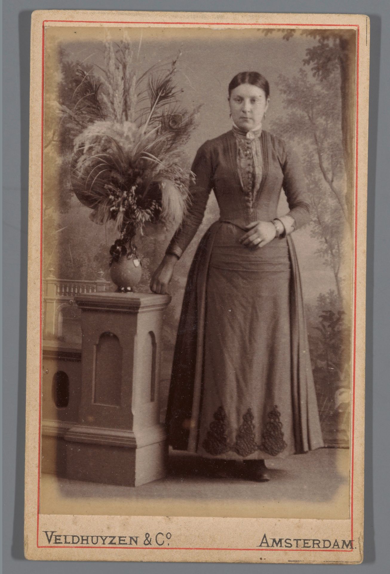 Portret van een onbekende vrouw staande naast een vaas met een droogboeket by Veldhuyzen & Co.