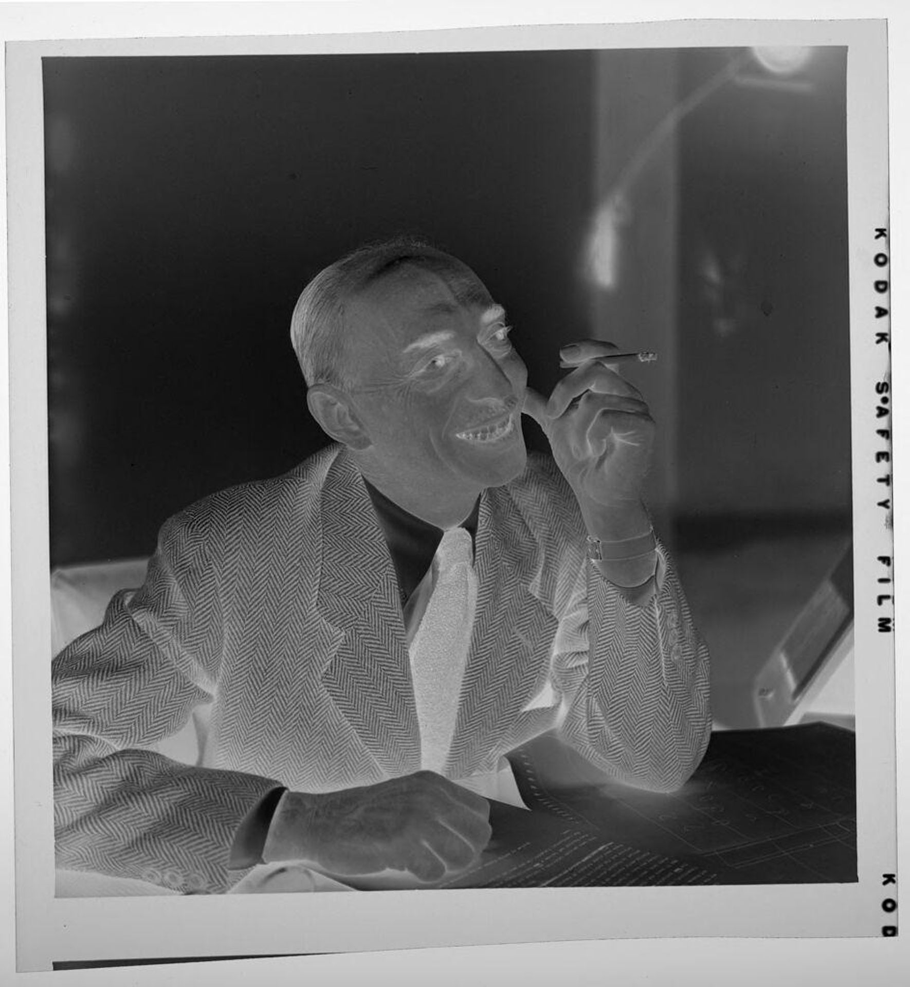 Untitled (man seated at table smiling and smoking cigarette) by Jack Gould