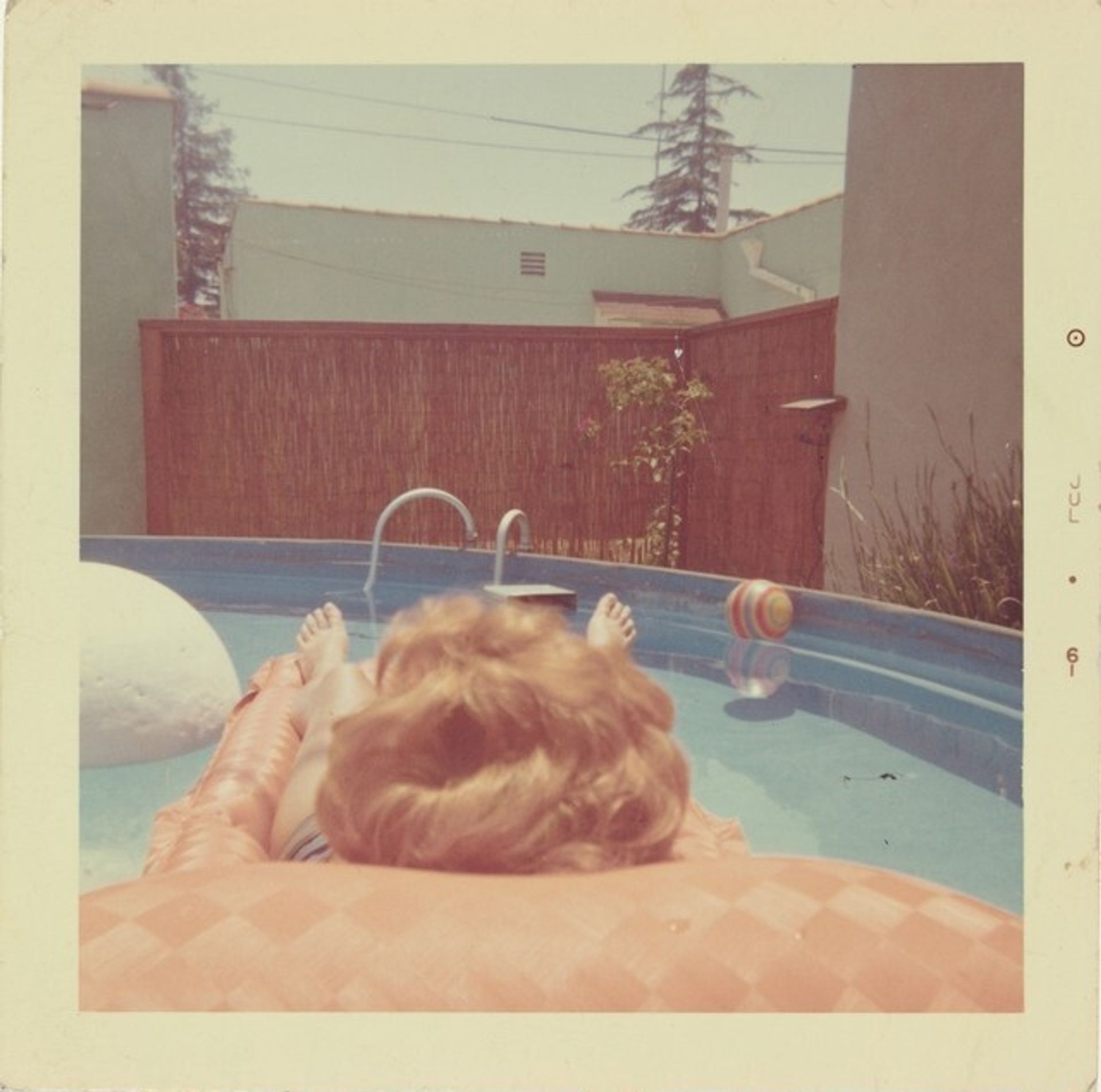 Untitled (Woman floating on raft in pool) by Anonymous