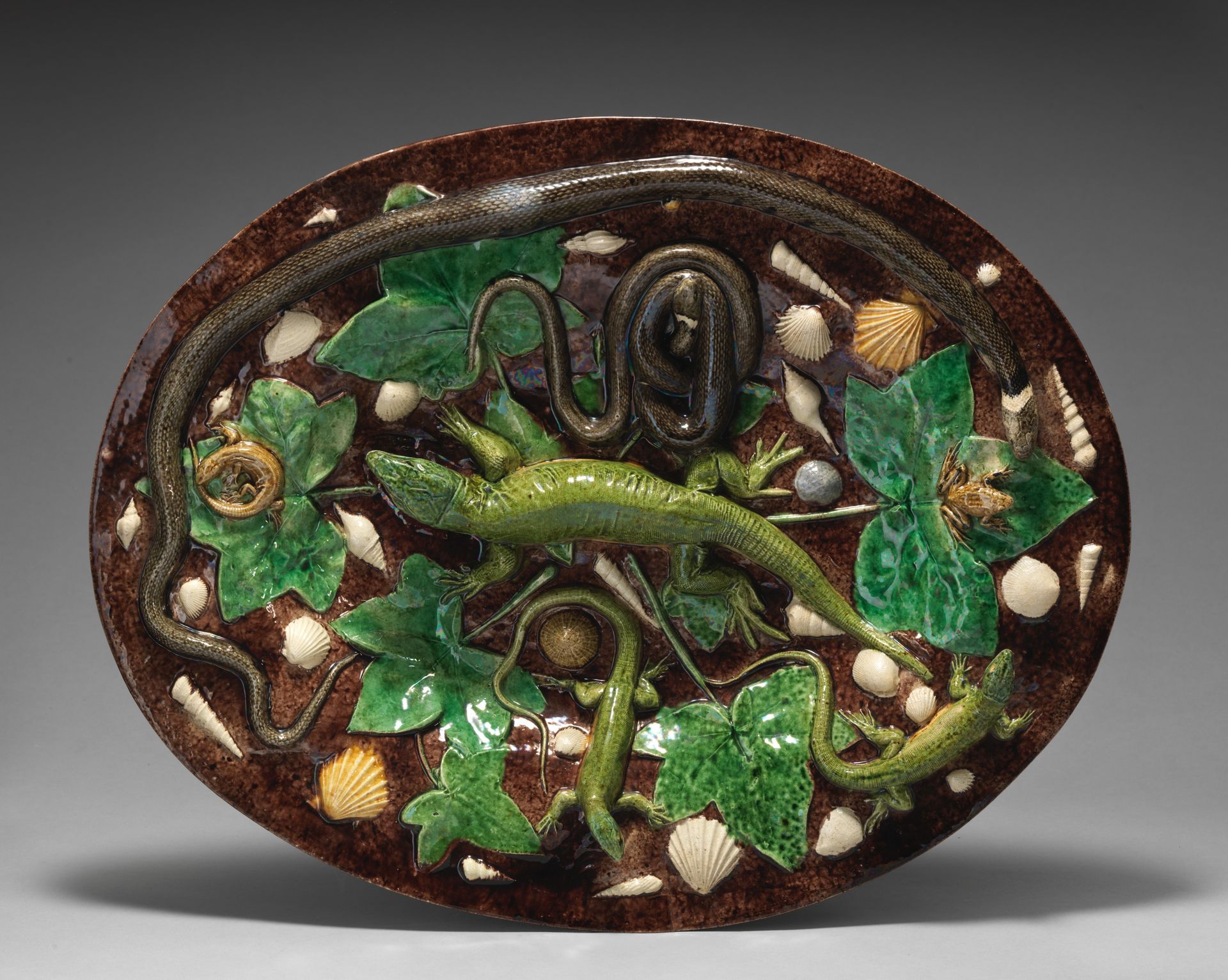 Oval basin with lizards, shells, and ivy leaves with brown background by Georges Pull