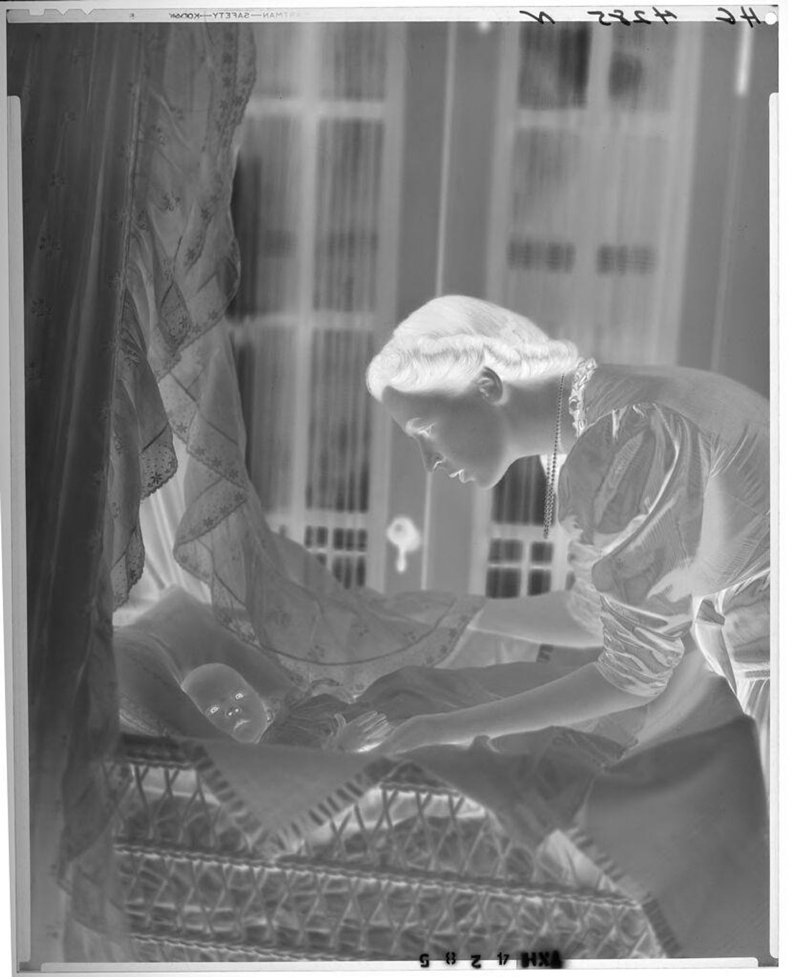 Untitled (woman leaning over baby from back of bassinet) by Paul Gittings