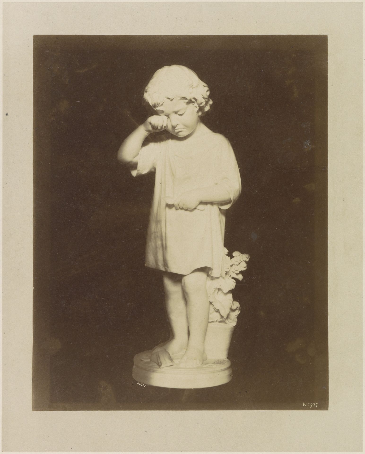 Sculptuur van een huilend kind voor een bak met bloemen by klösz