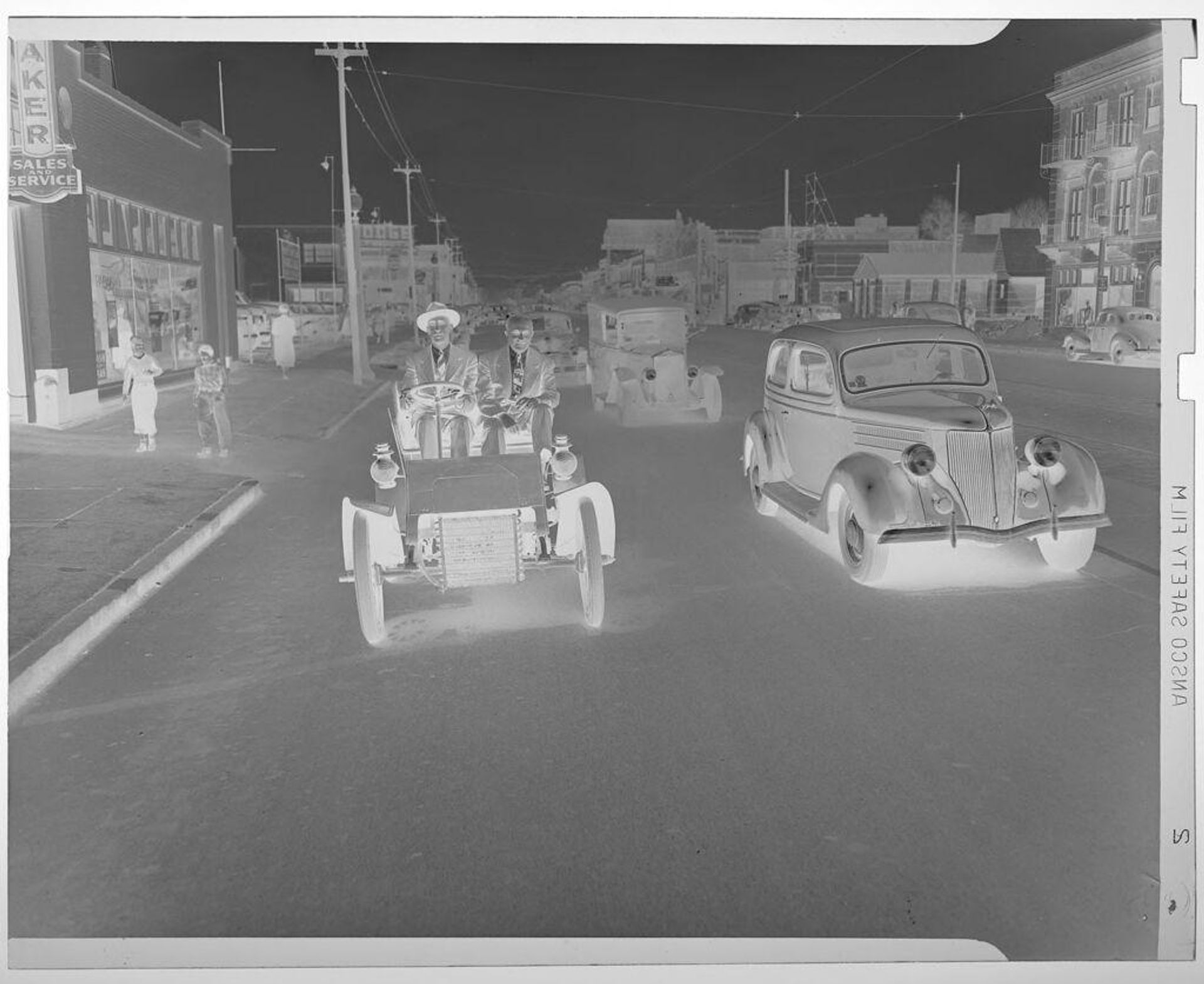 Untitled (men driving old car down city street) by Jack Gould