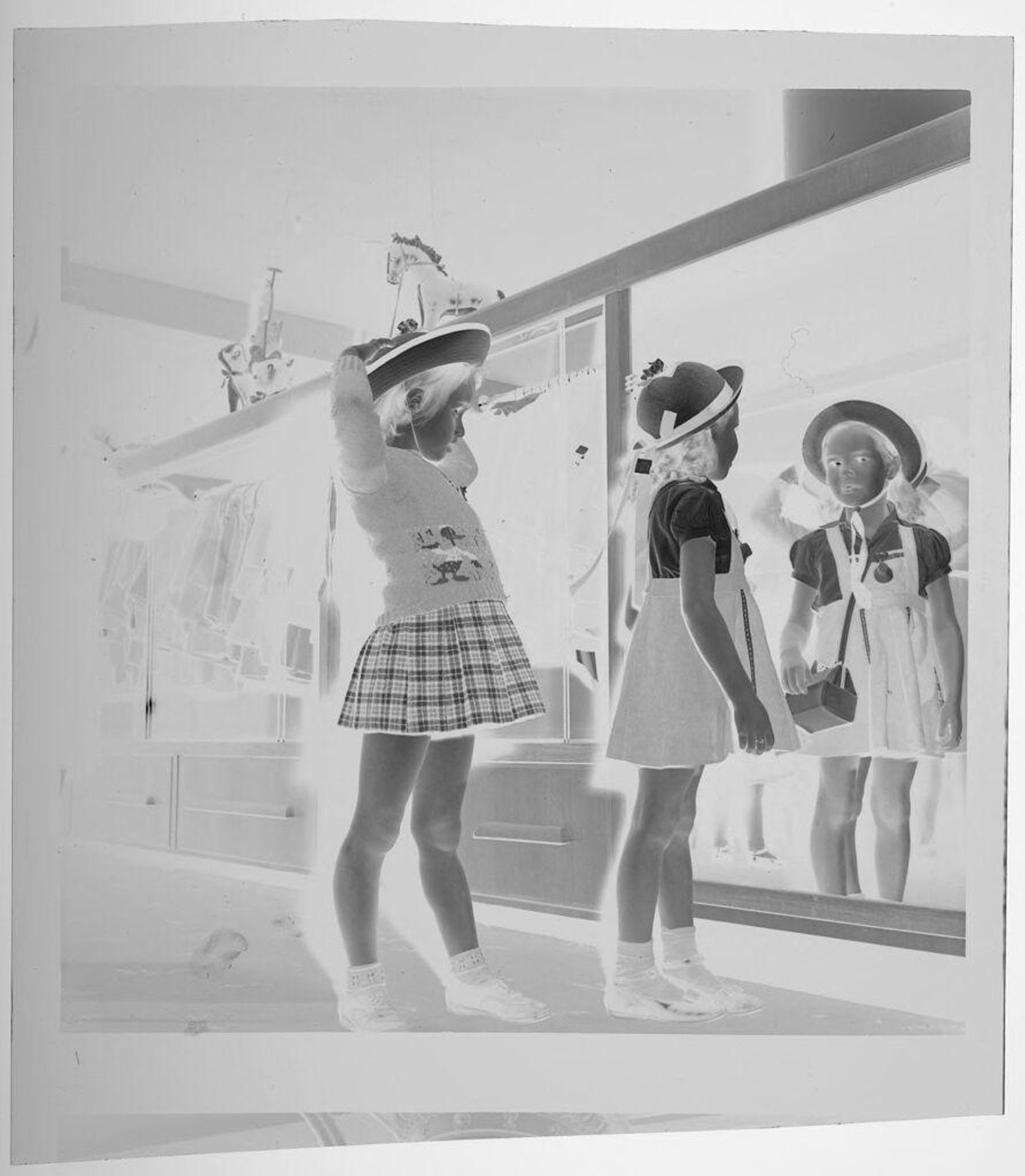 Untitled (young girls trying on hats in front of large store mirror) by Jack Gould