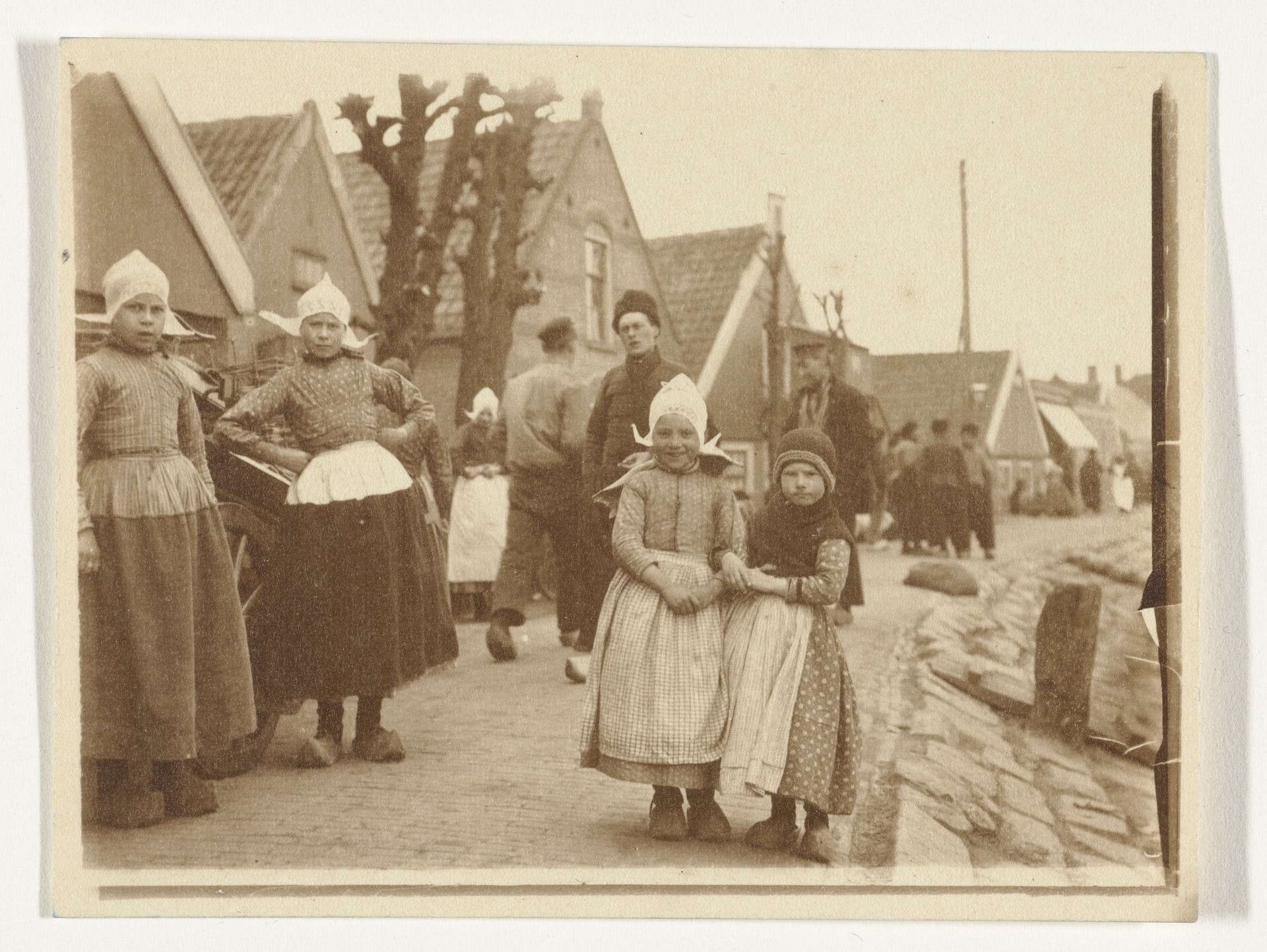 Mensen in klederdracht in Volendam, op de voorgrond enkele kinderen by G. Hidderley