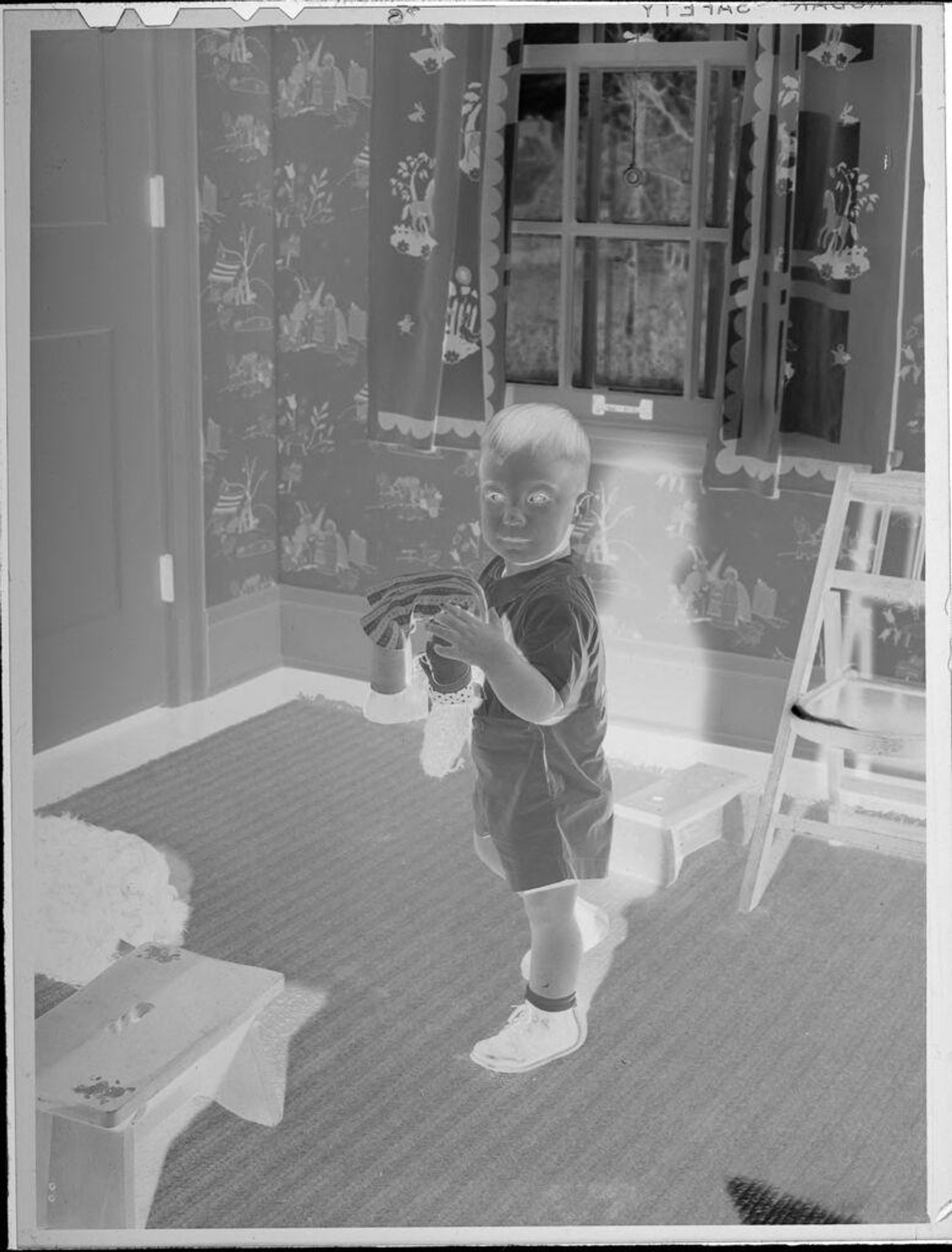 Untitled (little boy standing in bedroom, holding doll) by Lucian and Mary Brown