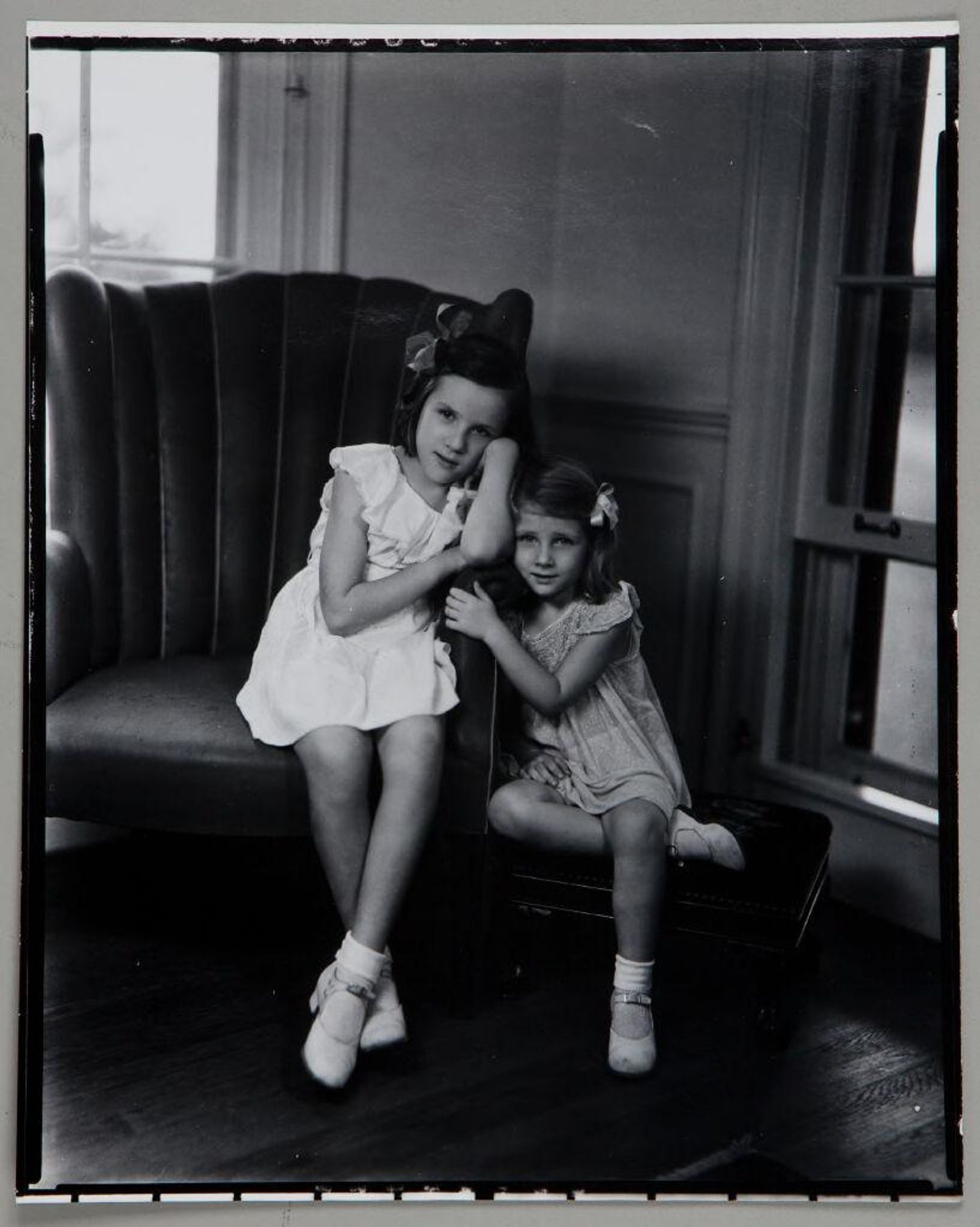 Untitled (two girls leaning toward each other, seated on chair and stool) by Paul Gittings