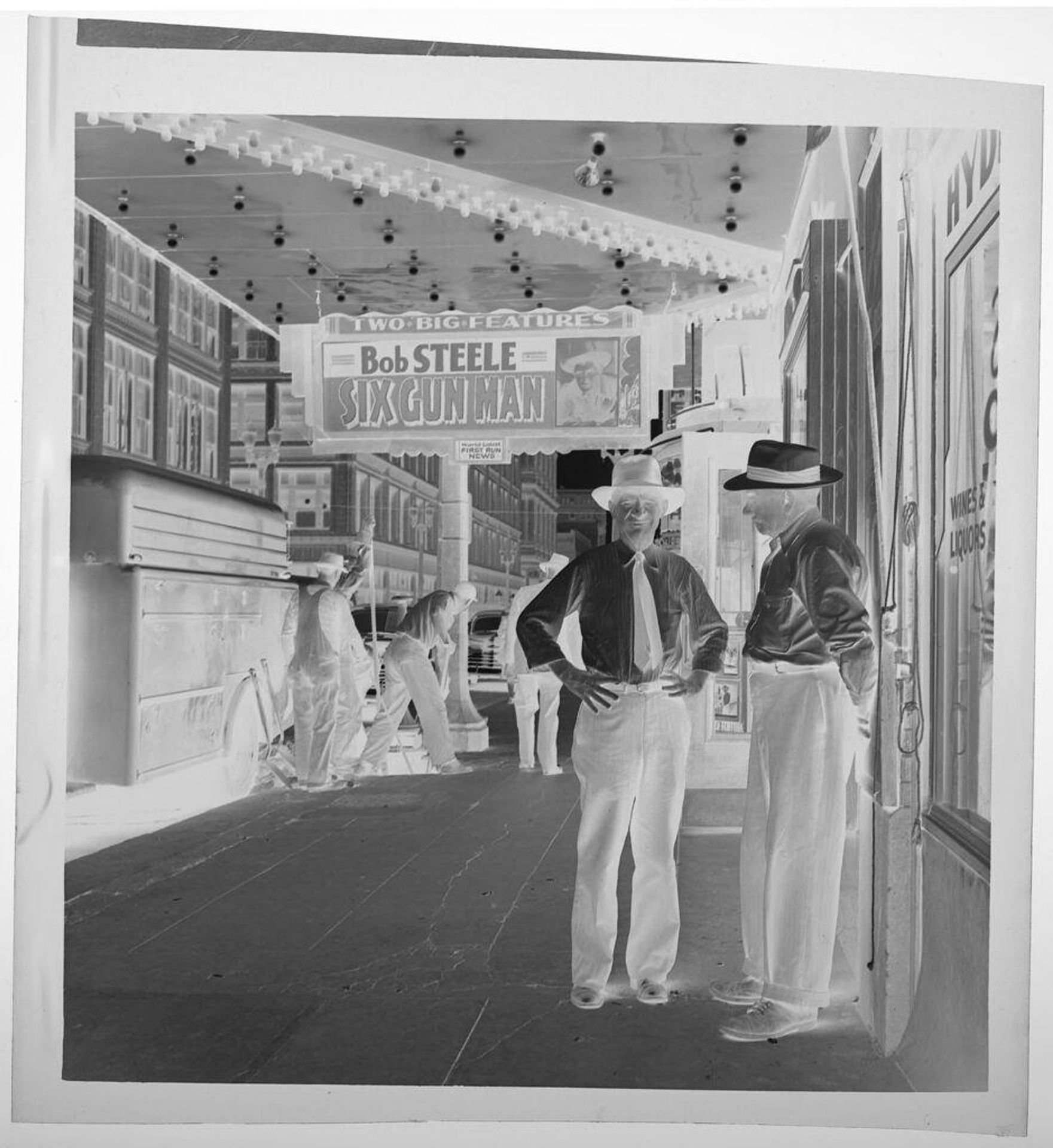 Untitled (two men standing outside of movie theater) by Jack Gould
