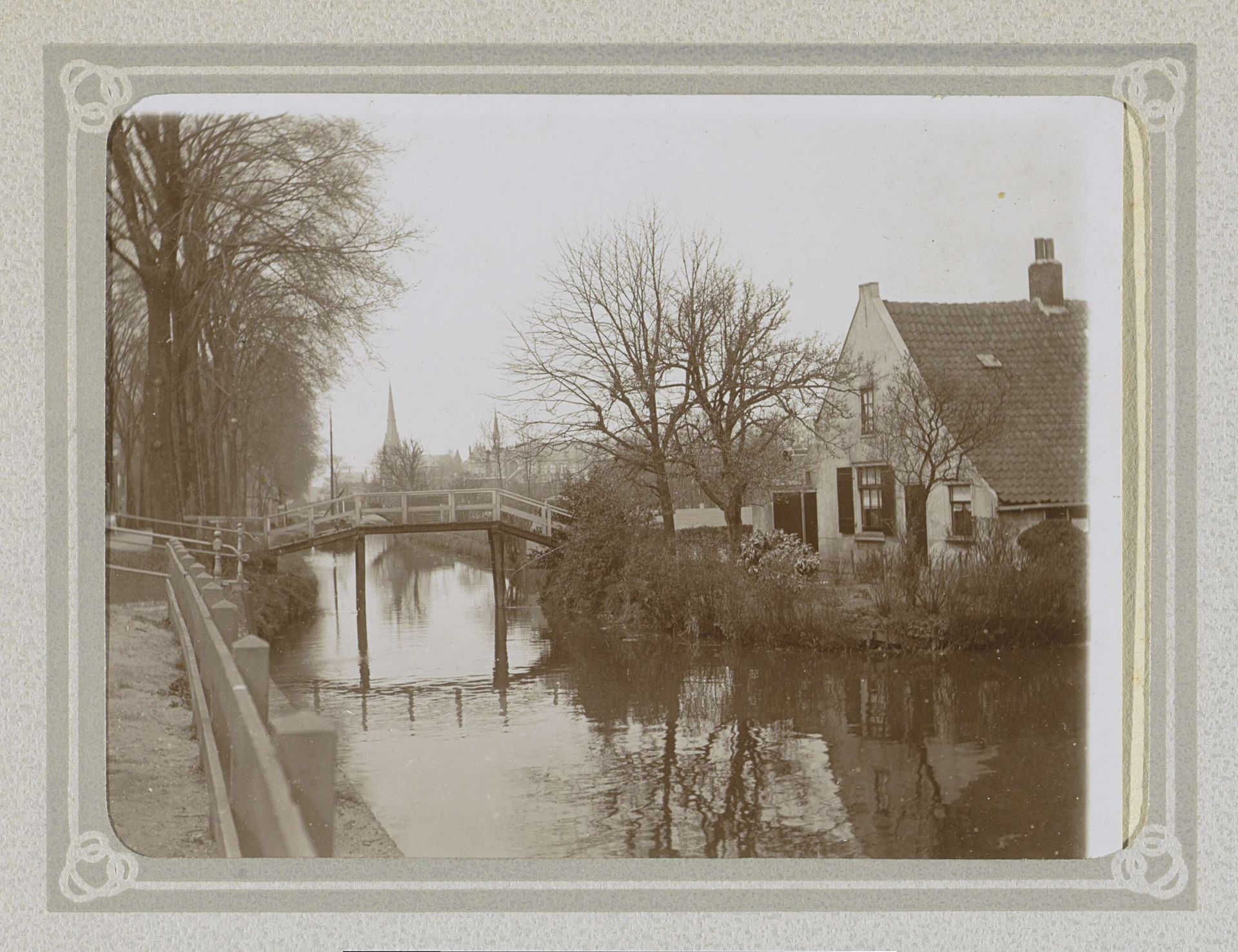 Huis aan een water met een brug, aan de horizon twee torens by Folkert Idzes de Jong