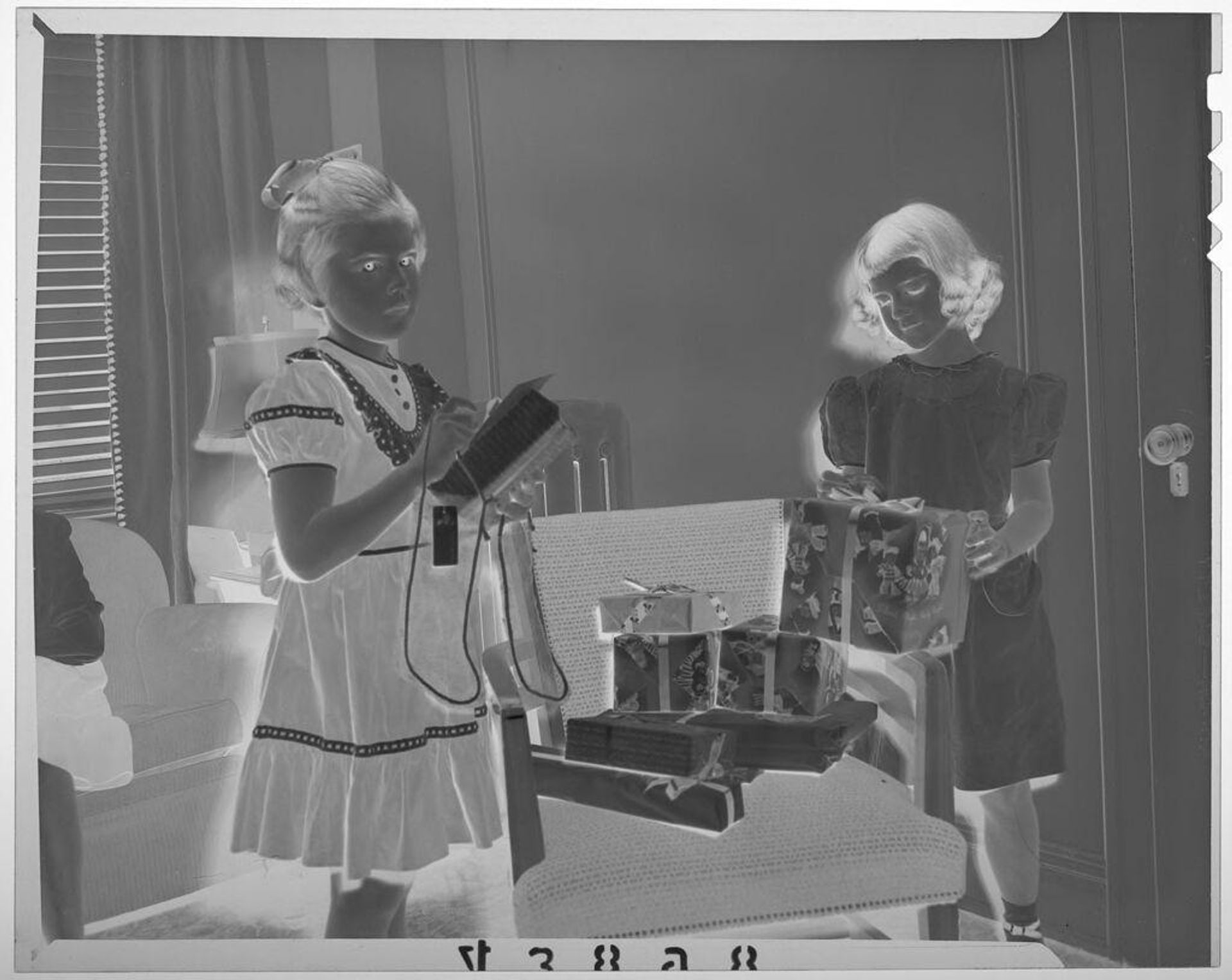 Untitled (two girls in dresses taking gifts from chair) by Martin Schweig