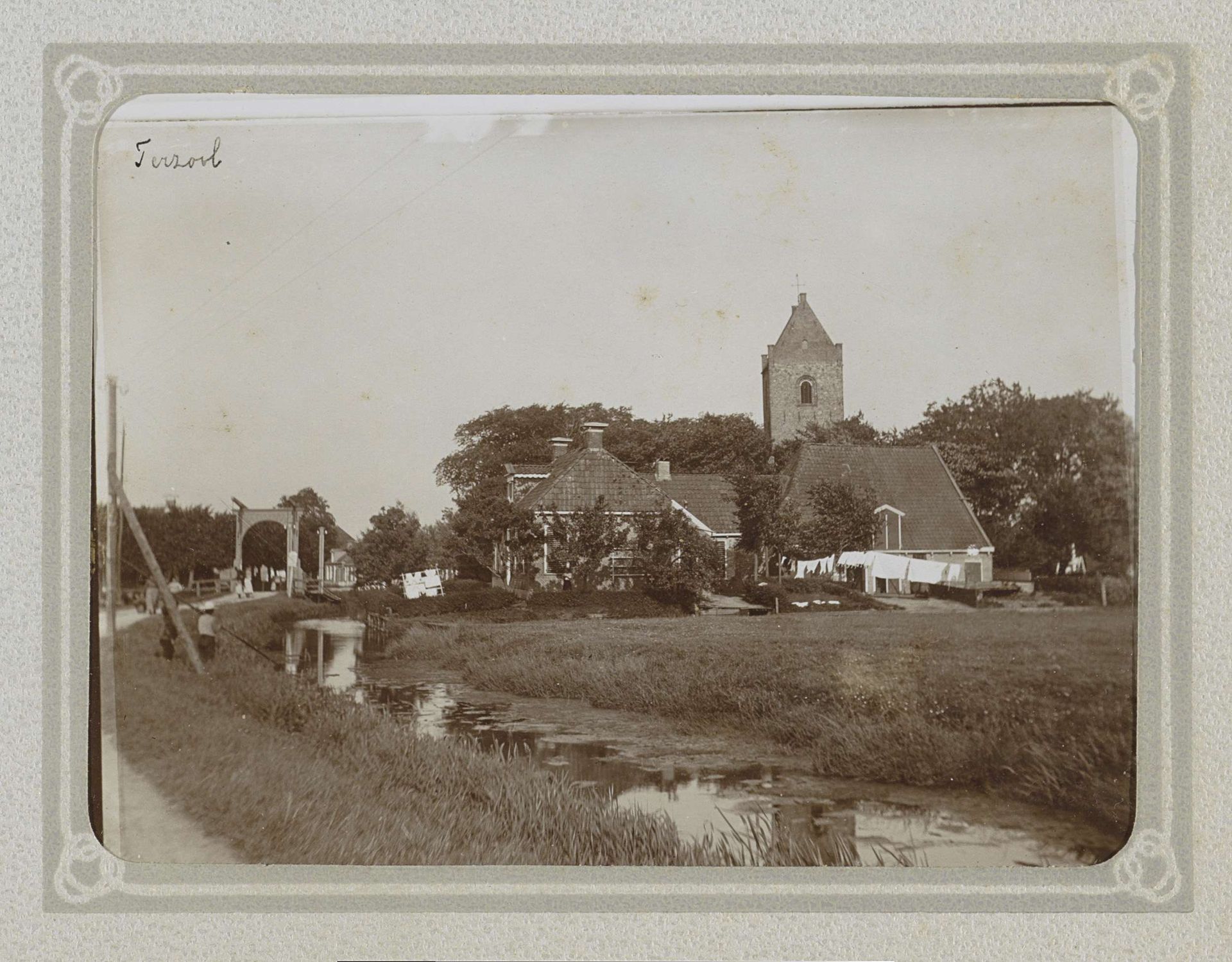 Gezicht op huizen, de kerk en een brug over een sloot in Terzool by Folkert Idzes de Jong